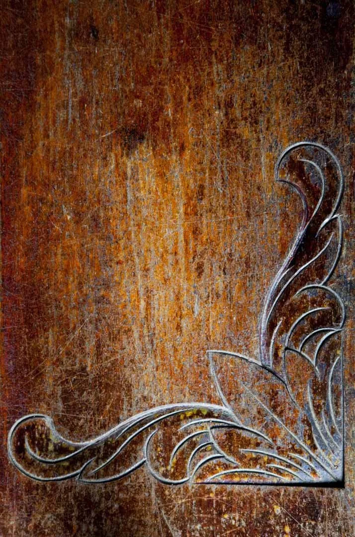 Decorative metal piece with curved lines on a distressed wooden surface.