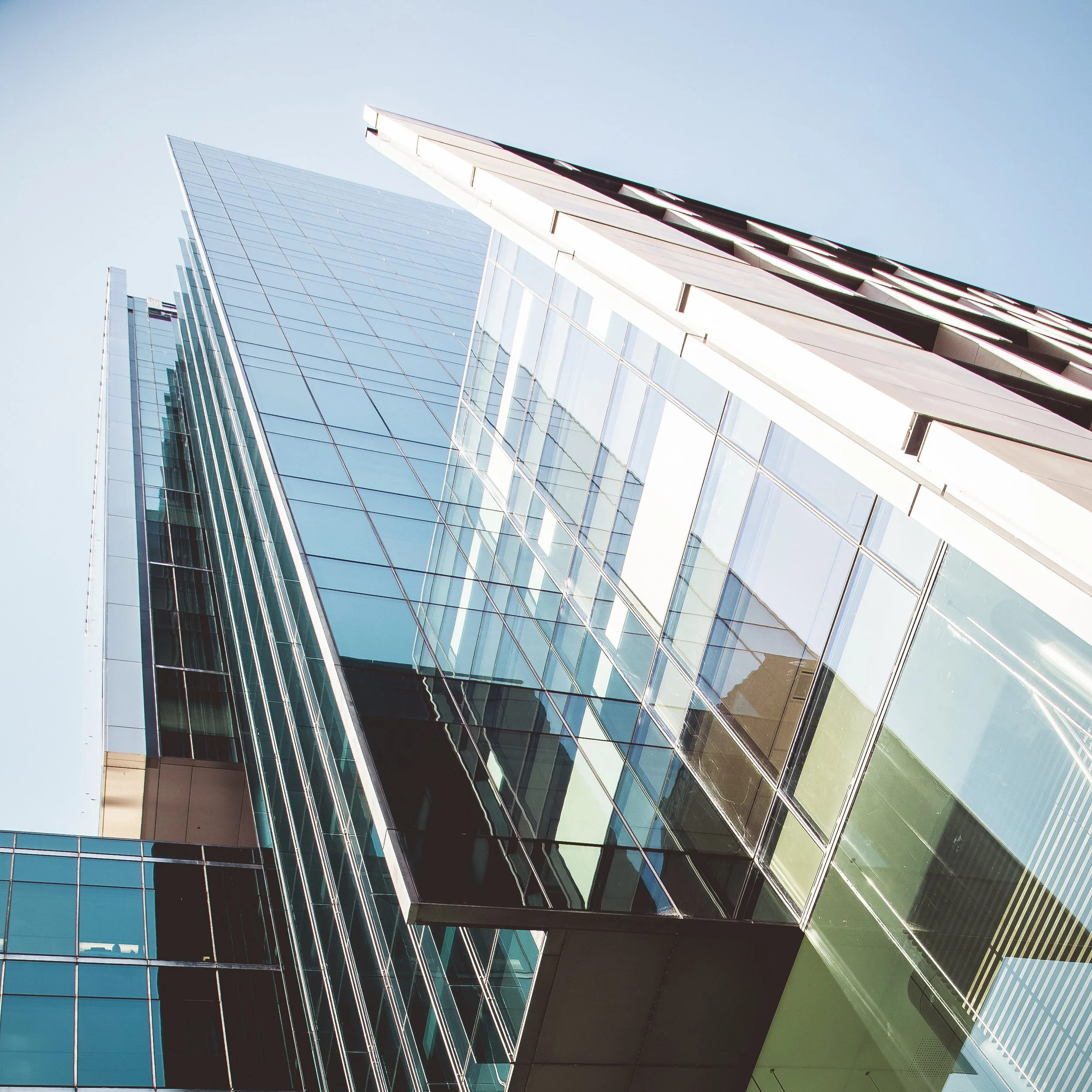 Looking up at a colorful glass building against blue skies