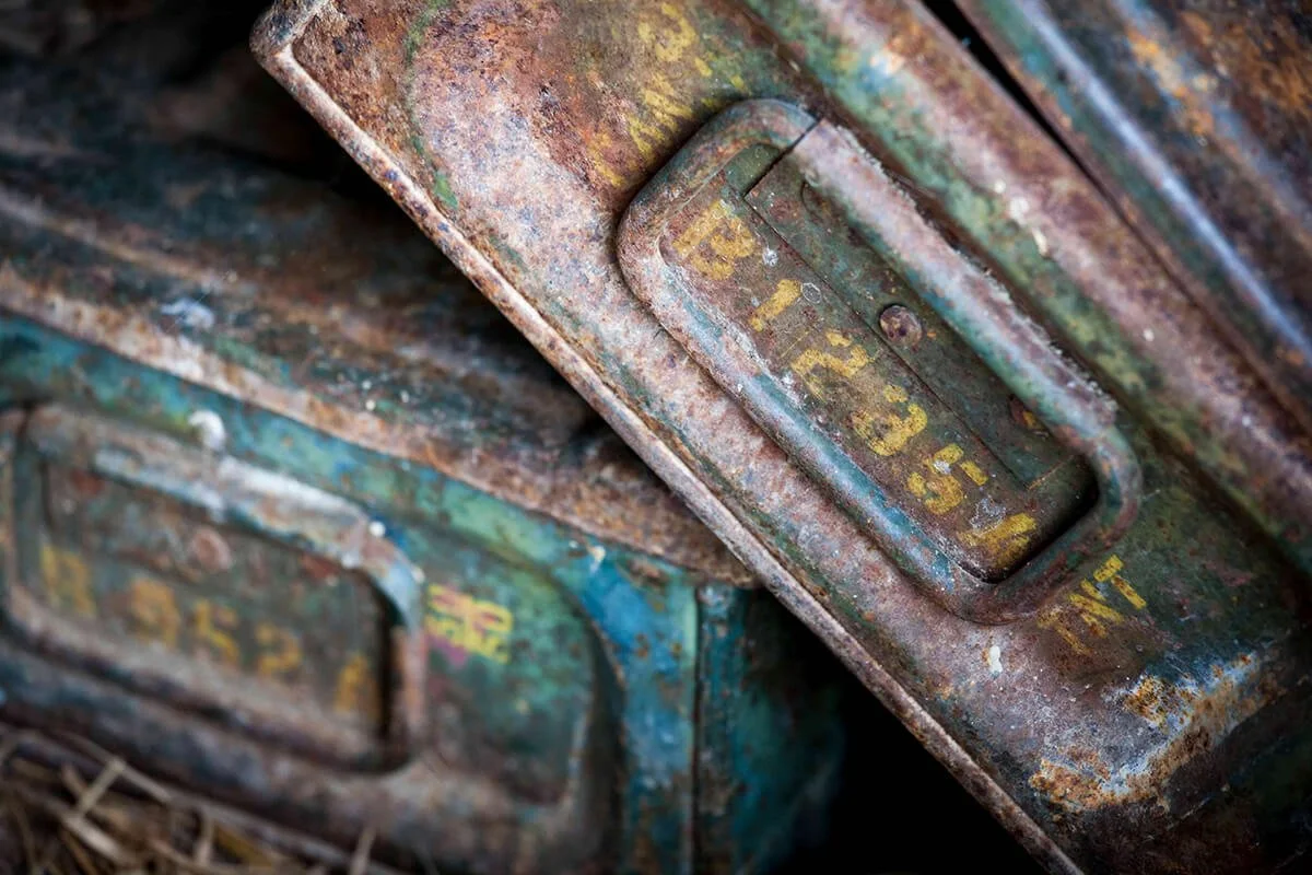 Close-up of heavily rusted metal containers with faded yellow and green paint, featuring weathered identification plates.