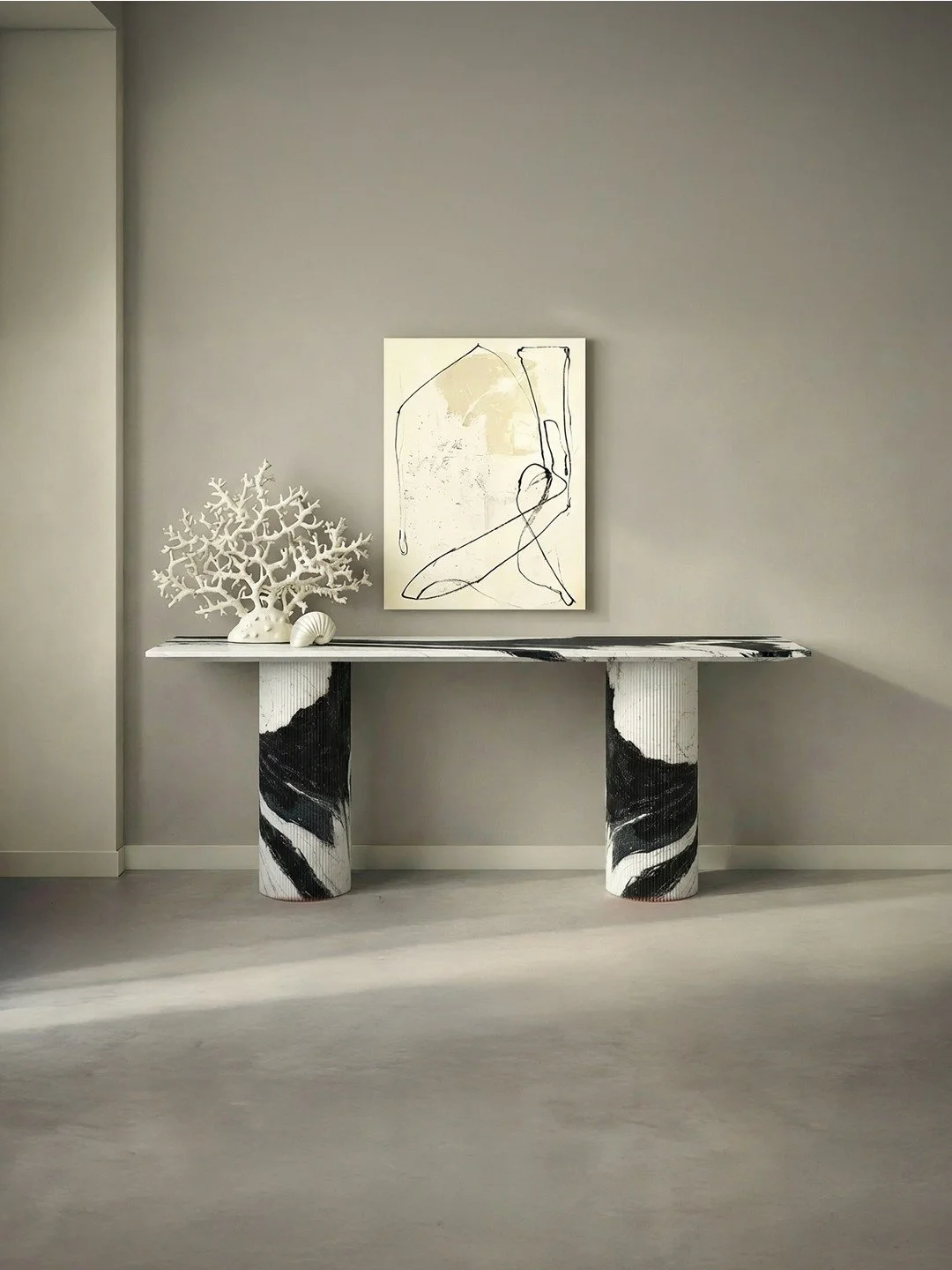 Une console en marbre noir et blanc avec des pieds cylindriques, décorée d'une sculpture en forme d'arbre blanc, d'une coquille blanche et d'une œuvre d'art abstraite suspendue sur un mur gris dans un intérieur moderne et minimaliste.