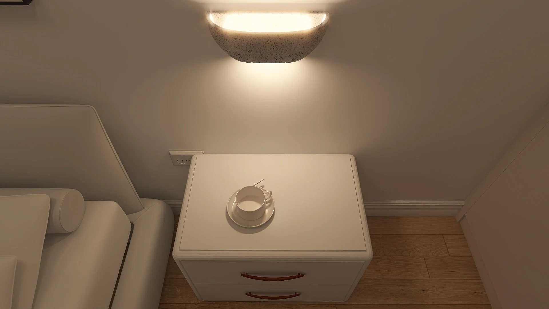 A white nightstand with two drawers and leather handles, set against a beige wall. On top of the nightstand, there is a white coffee cup on a saucer with an open spoon inside. Above, a wall-mounted light fixture with a speckled, half-sphere shape emi