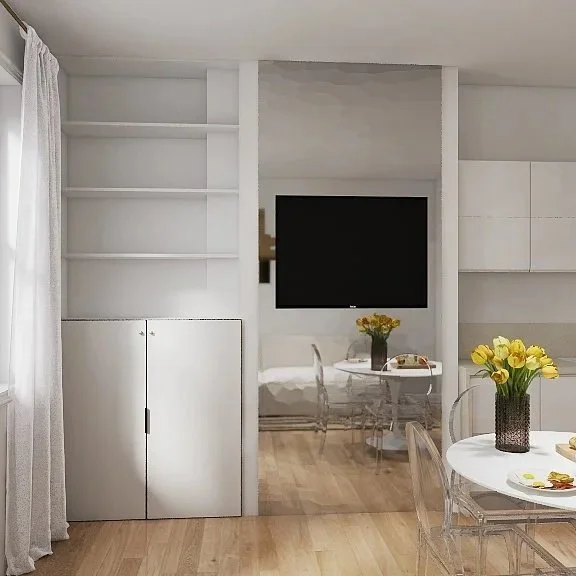 Living room with white walls, a mounted flat-screen TV, a small glass dining table with a vase of yellow flowers, and transparent dining chairs. Part of a round table with a vase and flowers is also visible.