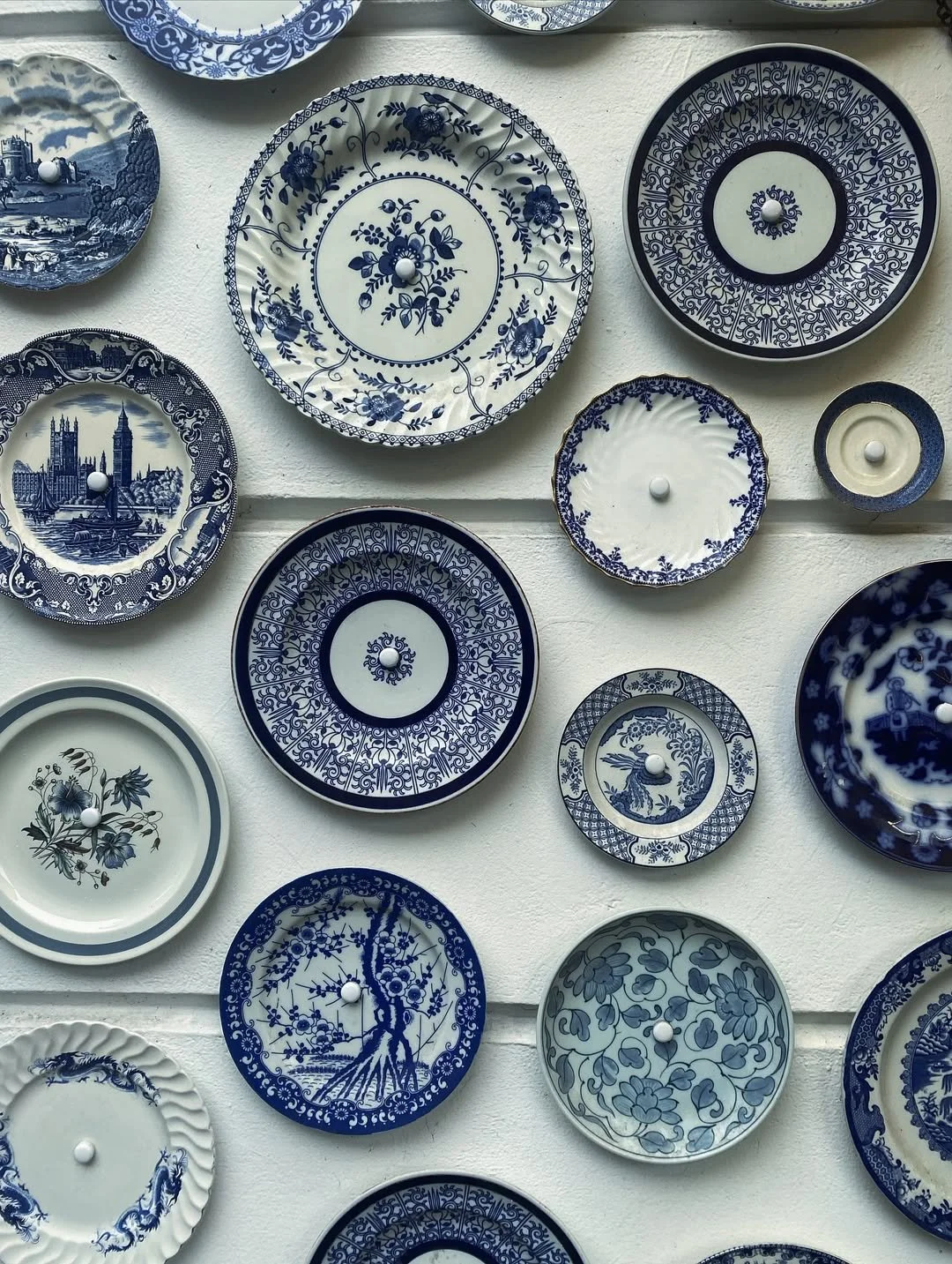 Collection of decorative blue and white ceramic plates displayed on a wall.