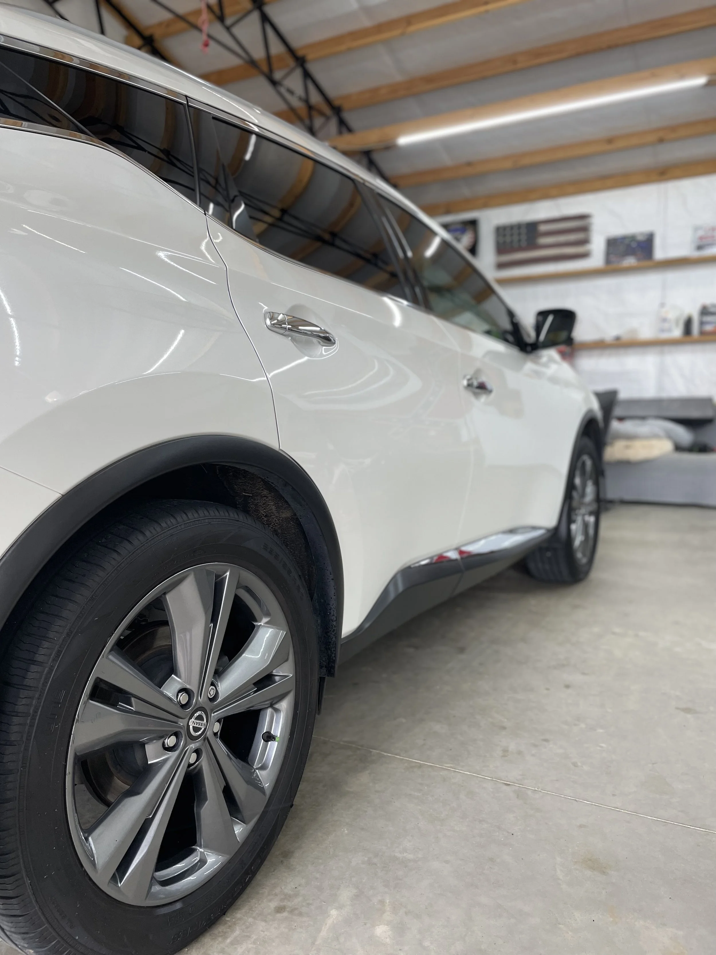 Silver GMC SUV parked on a driveway with trees and grass in the background.