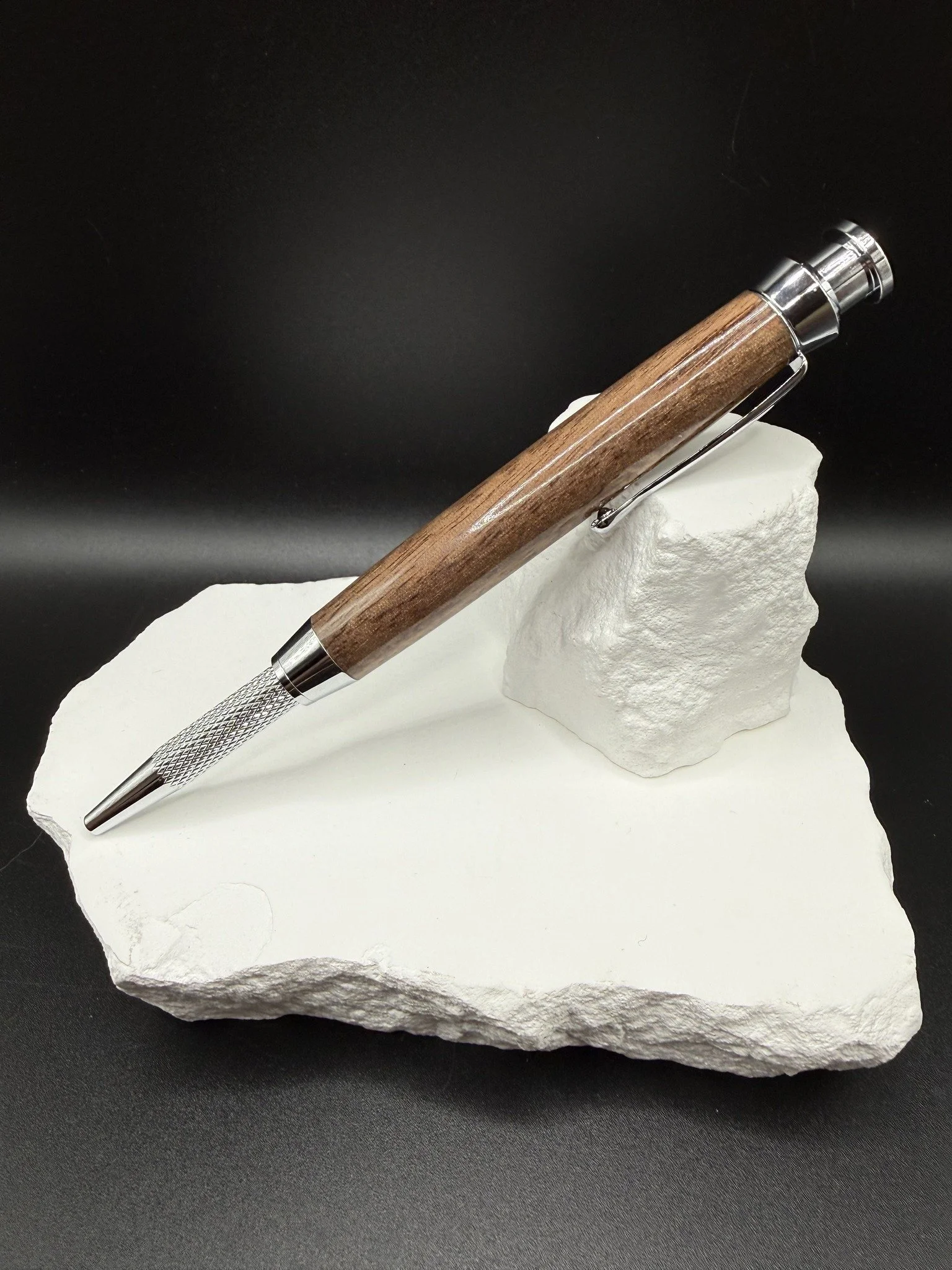Wood carpenter pencil resting on a piece of white rock with a black background.