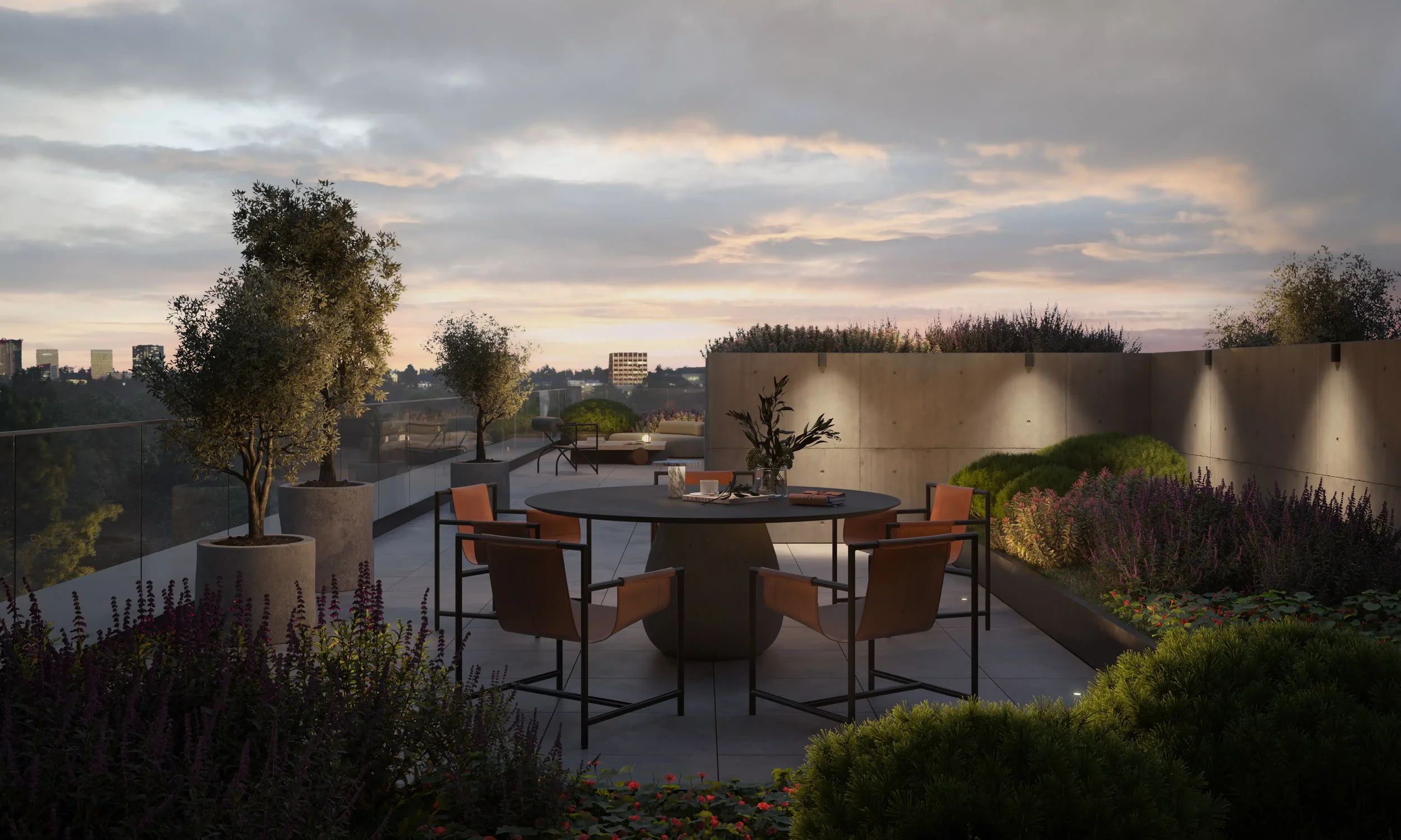 A rooftop patio at sunset with a round table, six chairs, potted trees, and a garden with purple and green plants, overlooking a city skyline under a cloudy sky.