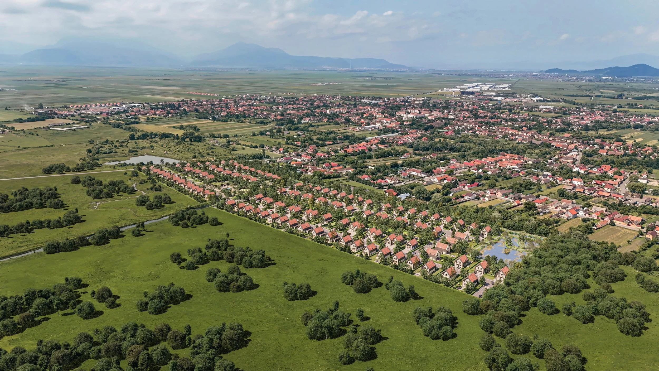 Aerial view of a suburban neighborhood with rows of houses, green fields, ponds, and distant mountains under a partly cloudy sky.