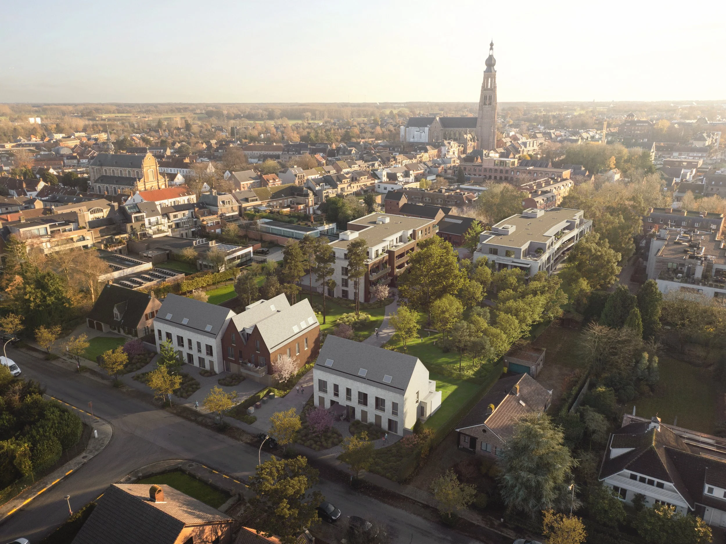 Aerial view of a city with a mix of modern and historical buildings, including a large church with a tall steeple, surrounded by trees and residential houses in warm sunlight.