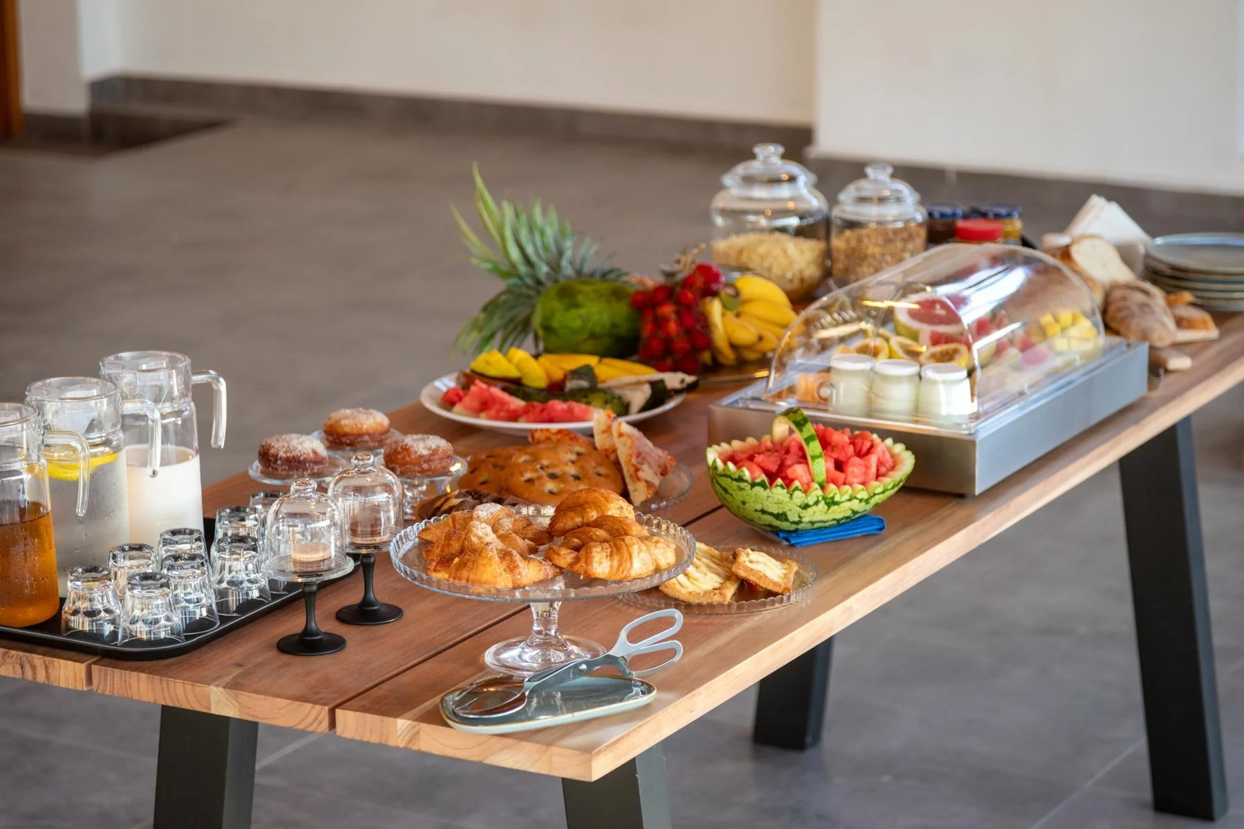 Buffet table filled with various fruits, pastries, and breakfast items. Outdoor dining set on the upper deck of Fort View luxury accommodation, overlooking the Old Fort, Stone Town, Zanzibar.
