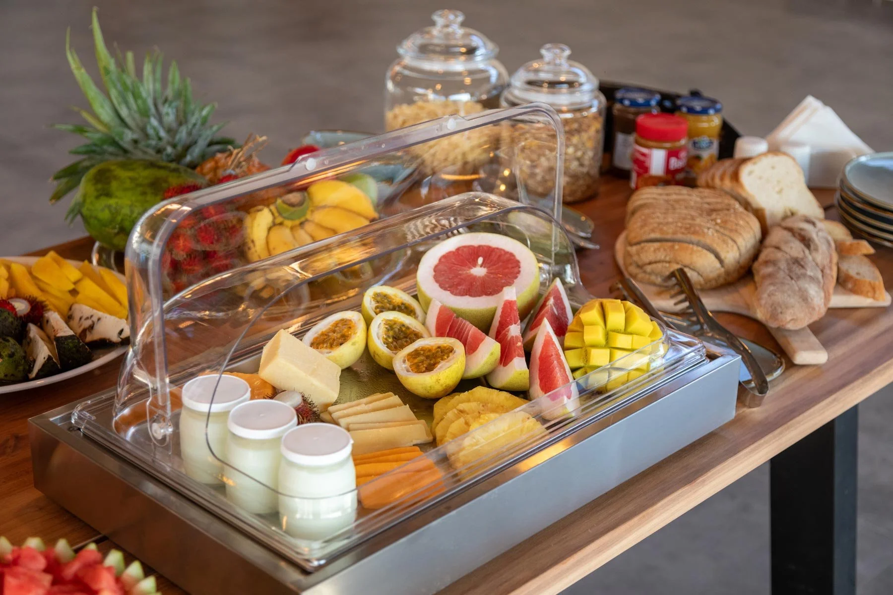 Buffet table filled with various fruits, pastries, and breakfast items. Outdoor dining set on the upper deck of Fort View luxury accommodation, overlooking the Old Fort, Stone Town, Zanzibar.
