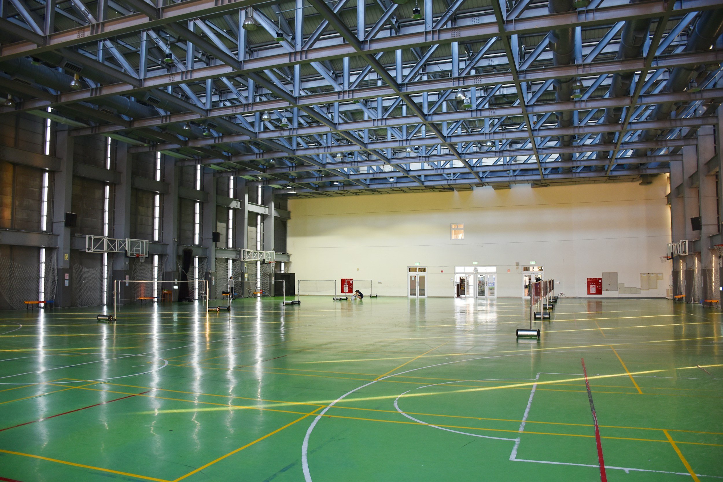 Pista cubierta de deportes con varias porterías y líneas de jugador en el suelo, en un espacio amplio con paredes altas y ventanas.
