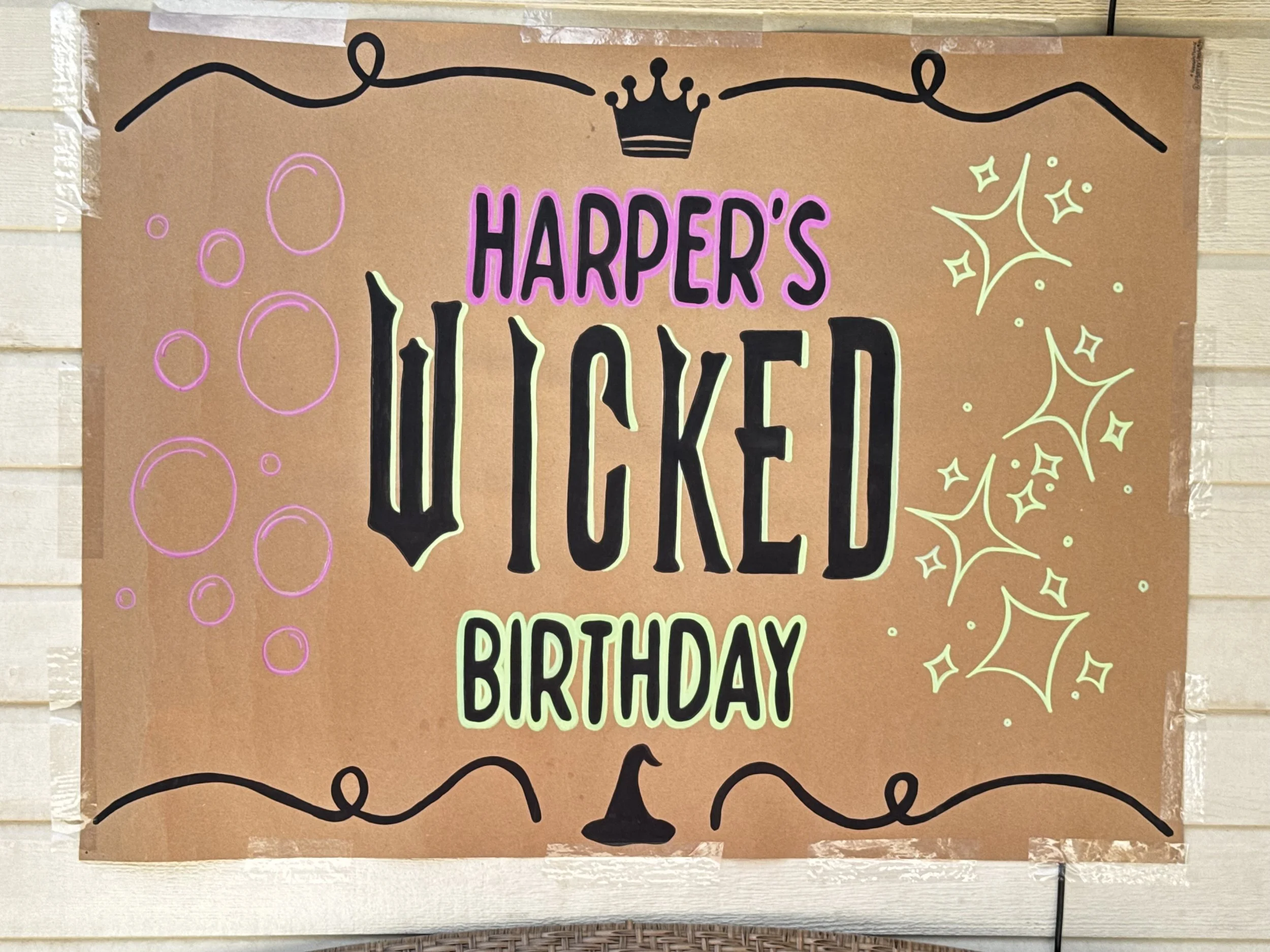 A birthday banner with black, pink, and yellow lettering and decorative elements on brown paper, celebrating Harper's birthday.