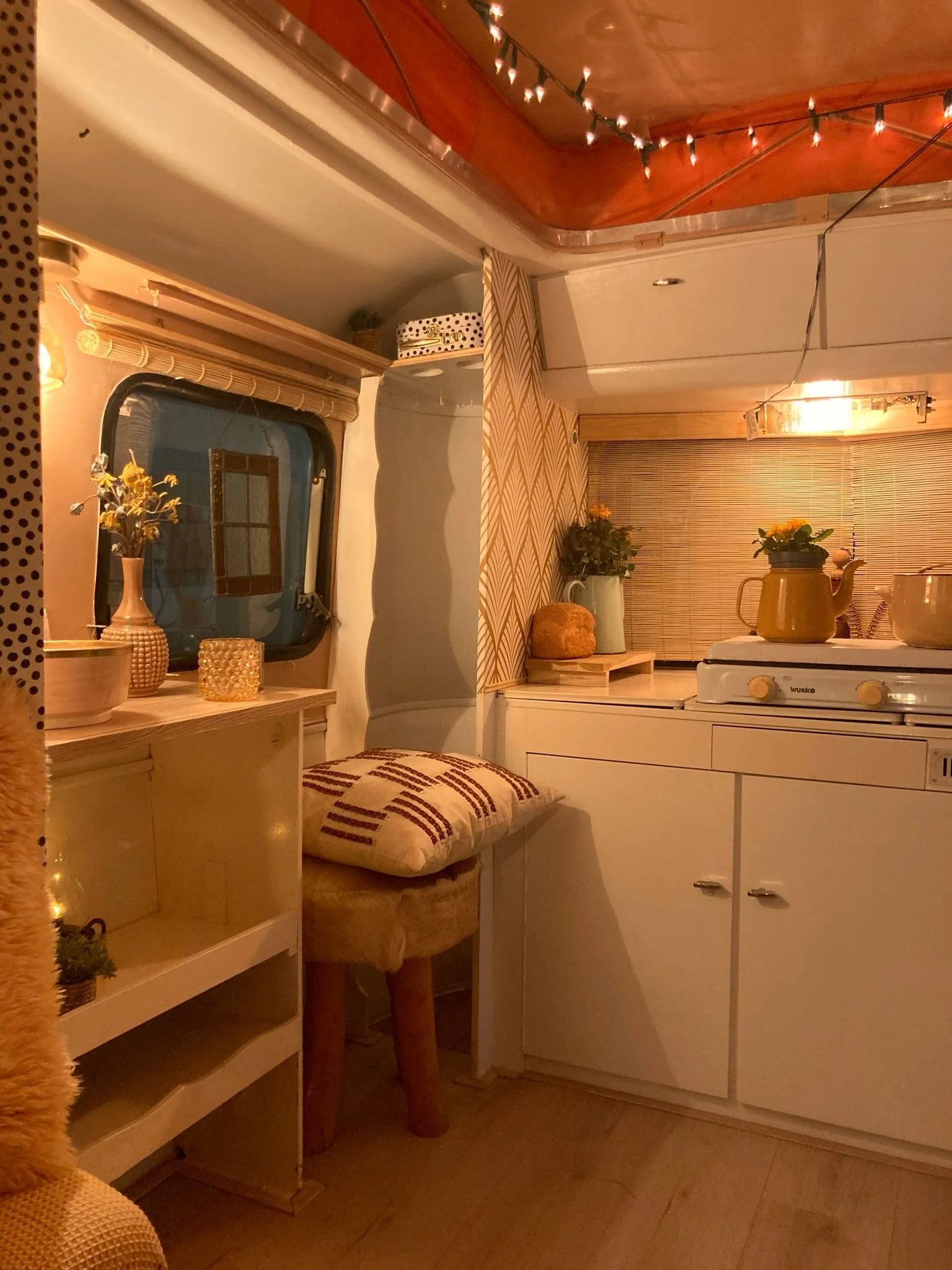 Een knusse keuken en zithoek in een woonwagen, versierd met lichtjes en bloemen.