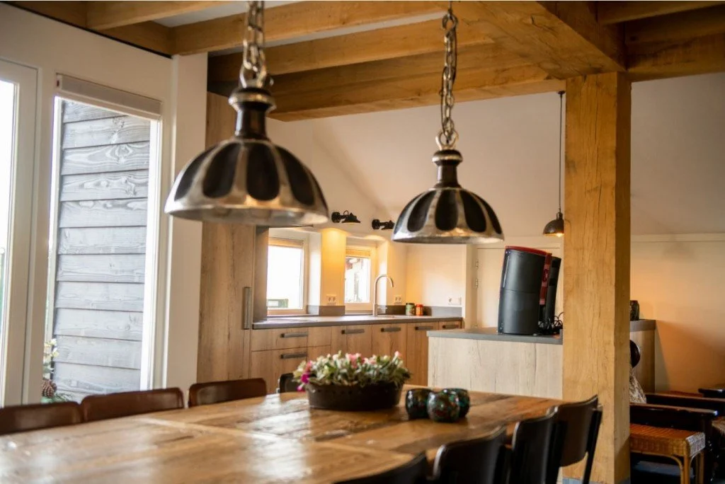 Interieur van een keuken en eetkamer met houten meubels en verlichting.