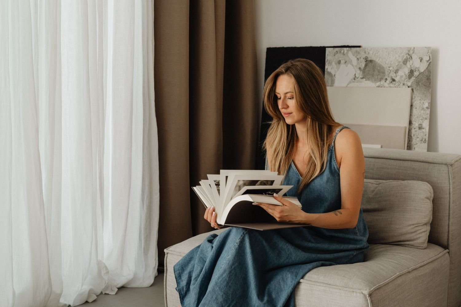woman sitting on couch flipping through design book