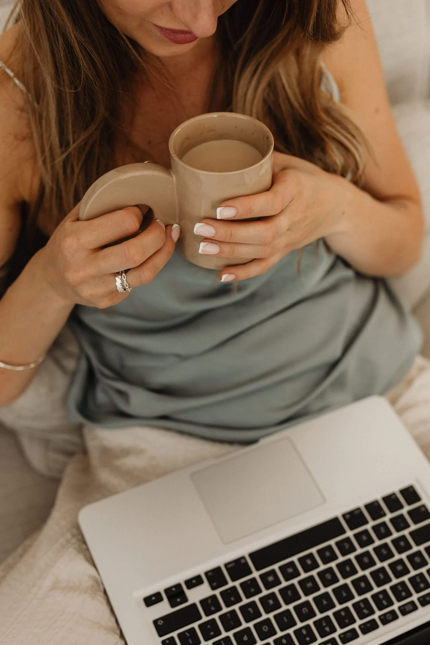 woman drinking coffee with laptop in lap