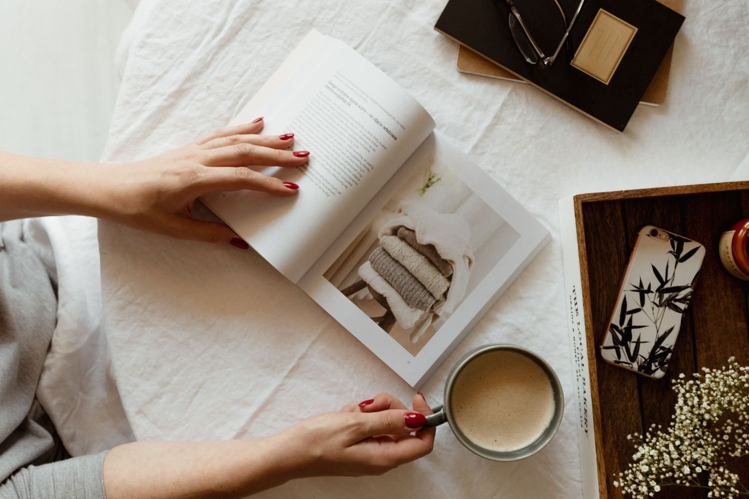 woman sitting at table with a design book and coffee