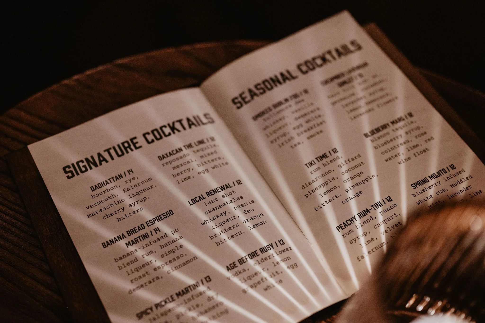 Open menu displaying cocktail recipes, including signature cocktails like 'Da Hartford,' 'Banana Bread Espresso Martini,' and 'Local Renewal,' with descriptions of ingredients and flavors.