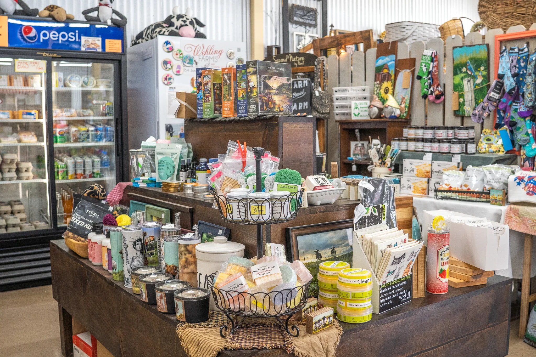 Inside a store with shelves and tables filled with various household and gift items, including candles, picture frames, soaps, and small decorative objects.
