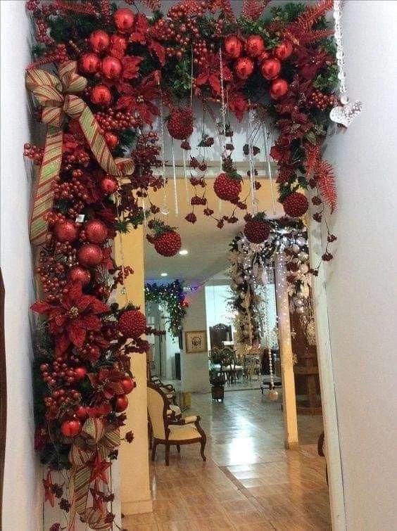 Festive Christmas holiday decoration with red ornaments, ribbons, and garlands decorating a doorway.