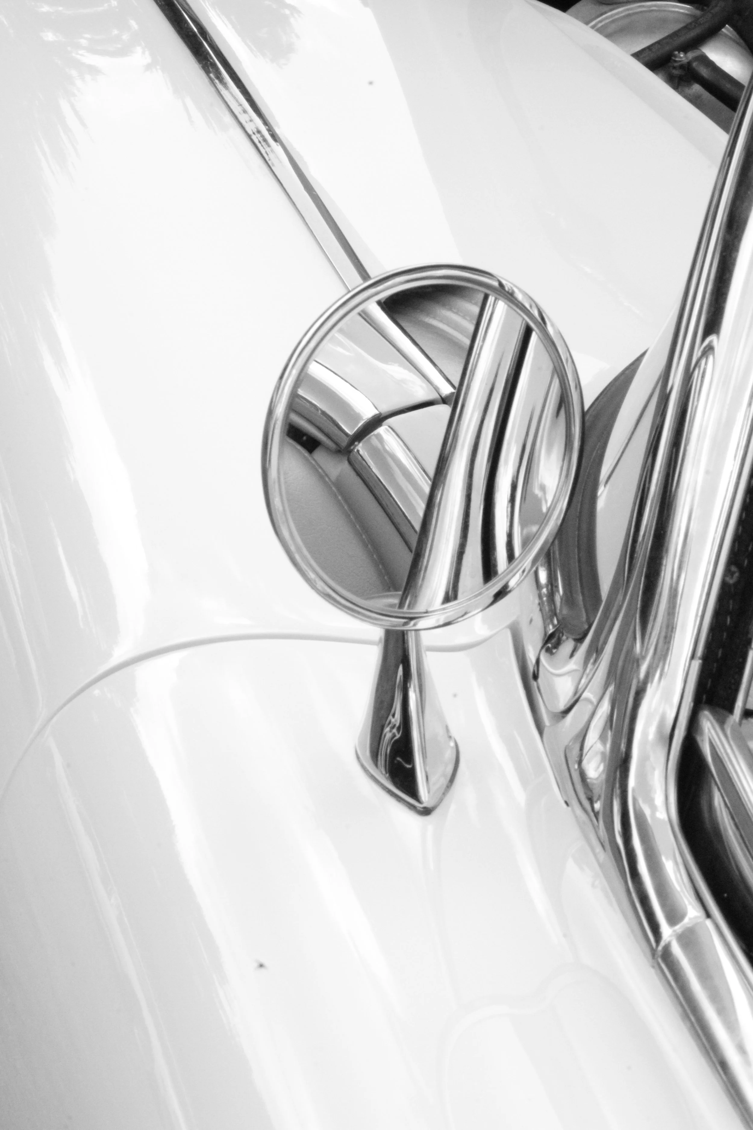 Close-up of a vintage car's front hood ornament and grille in black and white.