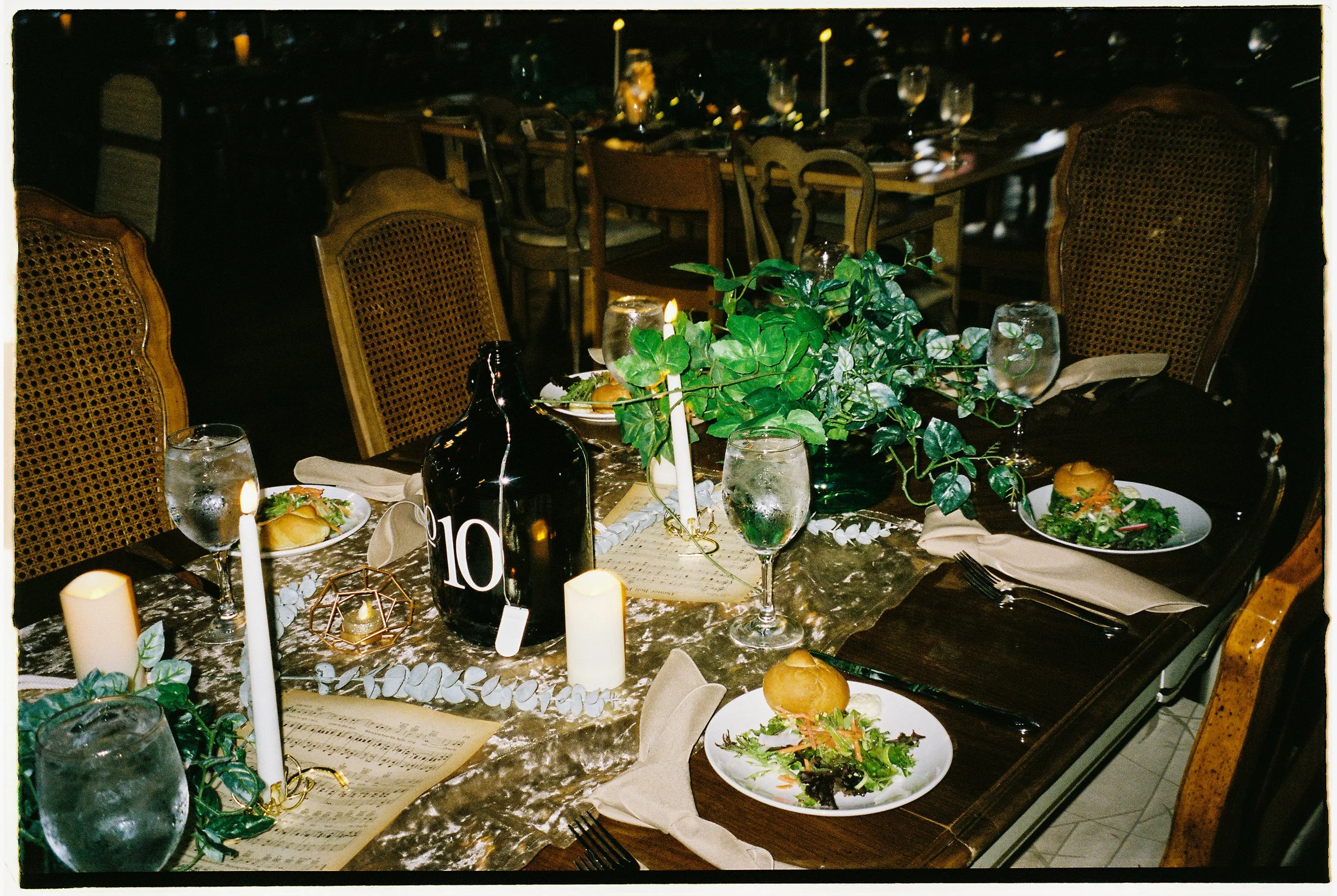 Reception table styled with candles, greenery, and vintage decor at Salvage One