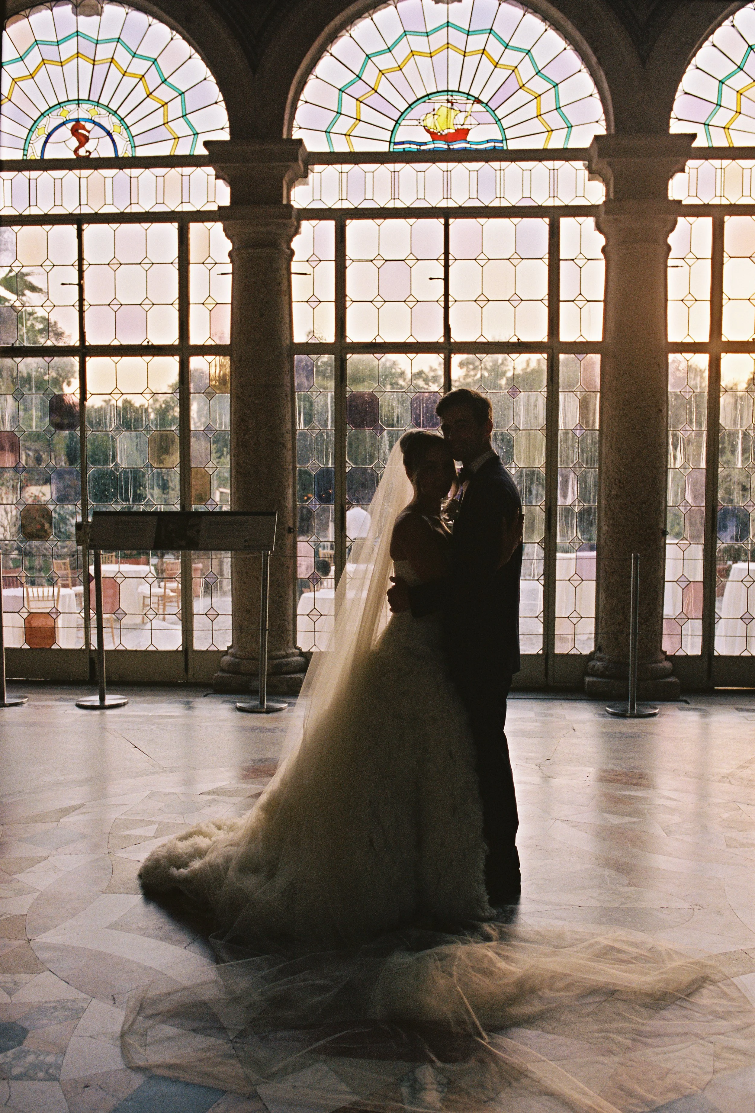 Silhouette of the bride and groom sharing a quiet moment in front of sunlit windows inside the historic estate. (Copy)