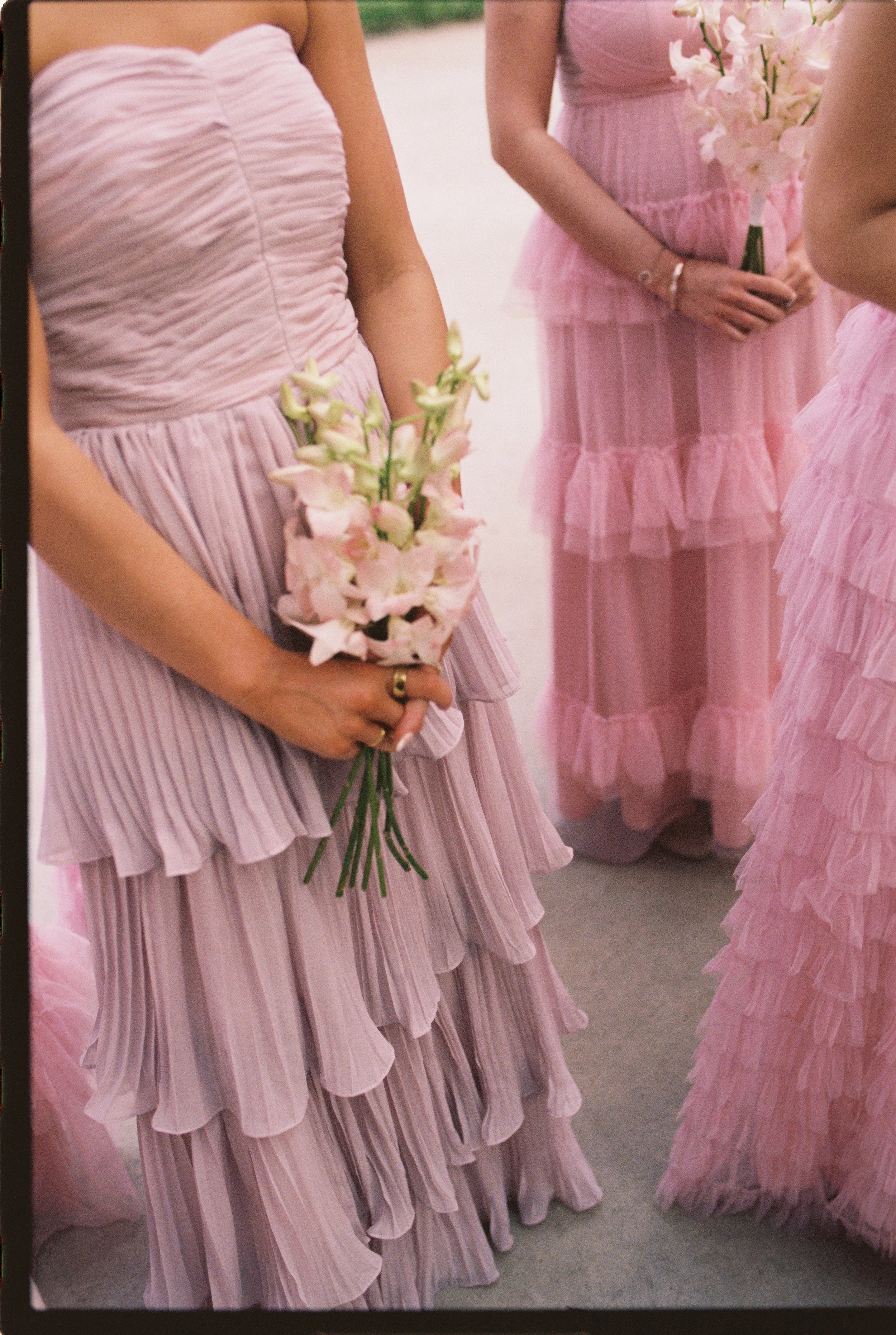 Bridesmaids in layered blush dresses holding delicate pink floral bouquets before the ceremony. (Copy)