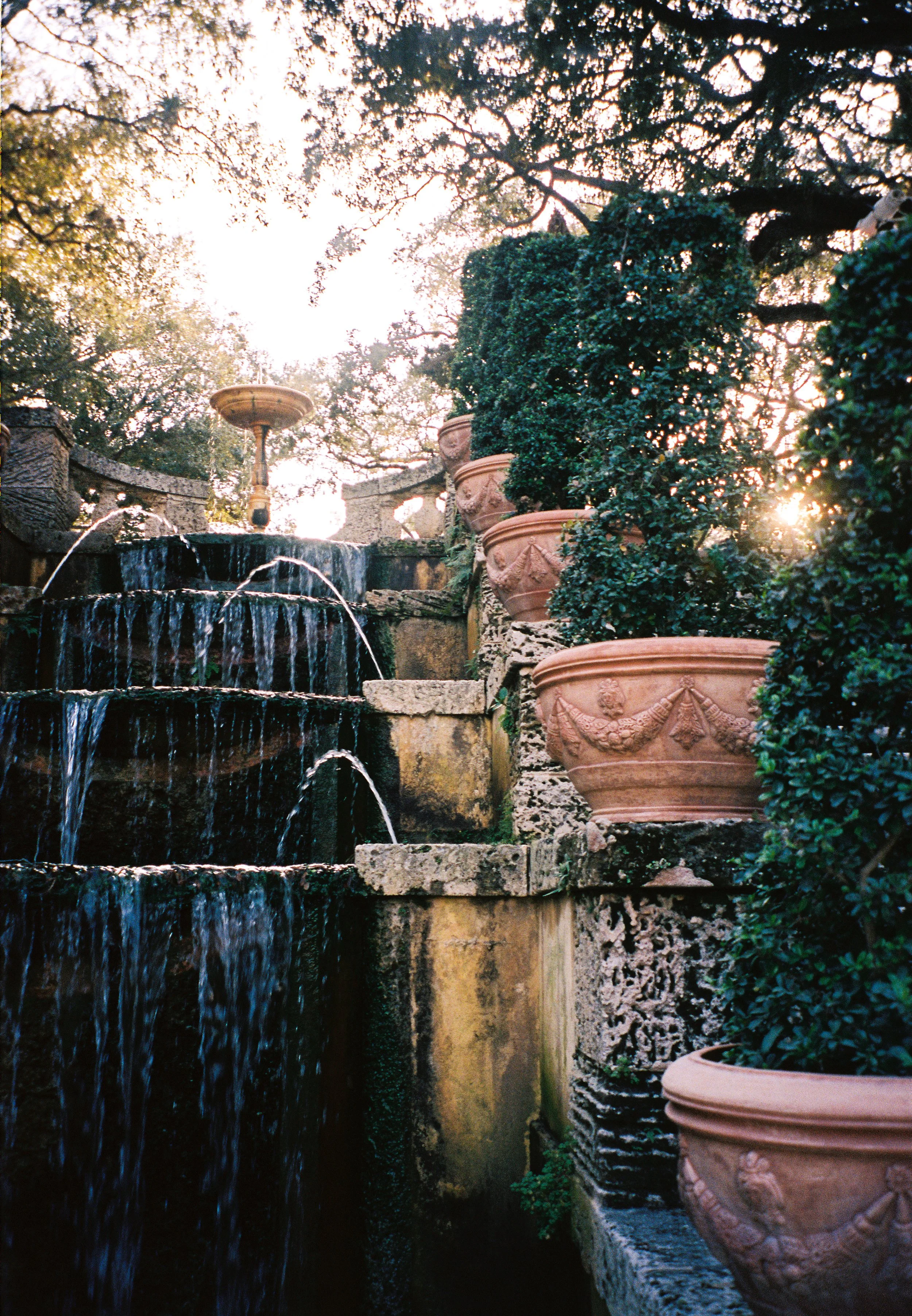 Tiered stone fountain surrounded by terracotta planters and lush greenery in the gardens at Vizcaya Museum and Gardens. (Copy)