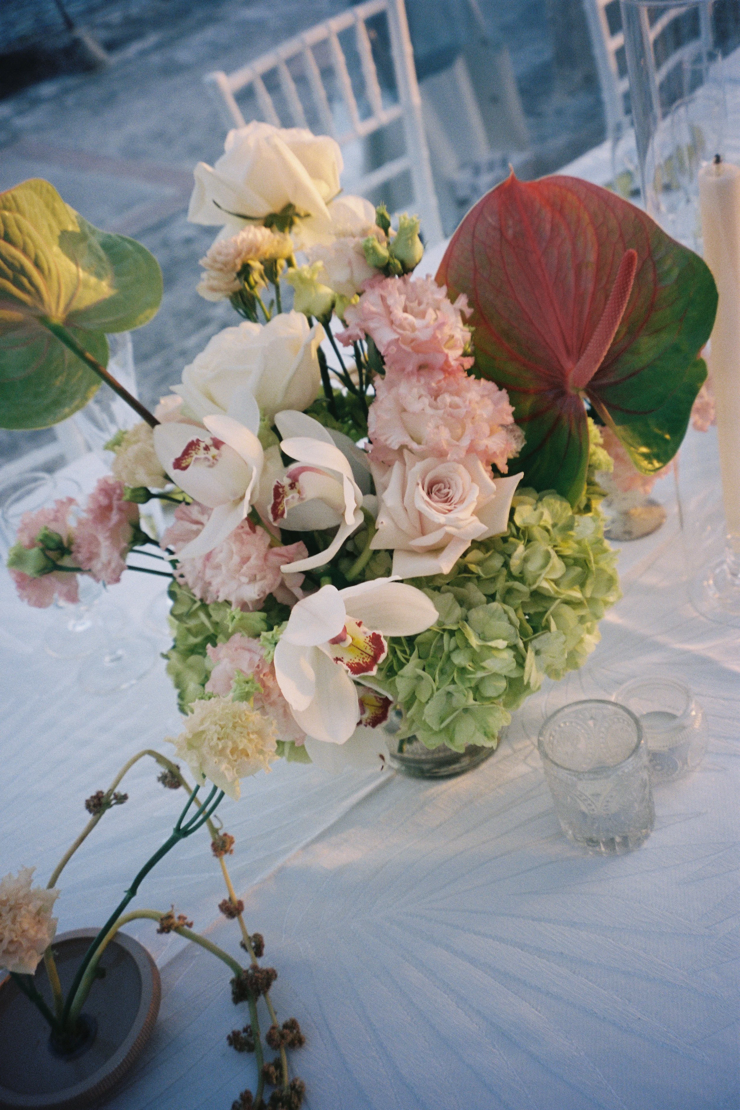 Romantic wedding table centerpiece featuring orchids, roses, and anthuriums during a reception at Vizcaya Museum and Gardens. (Copy)