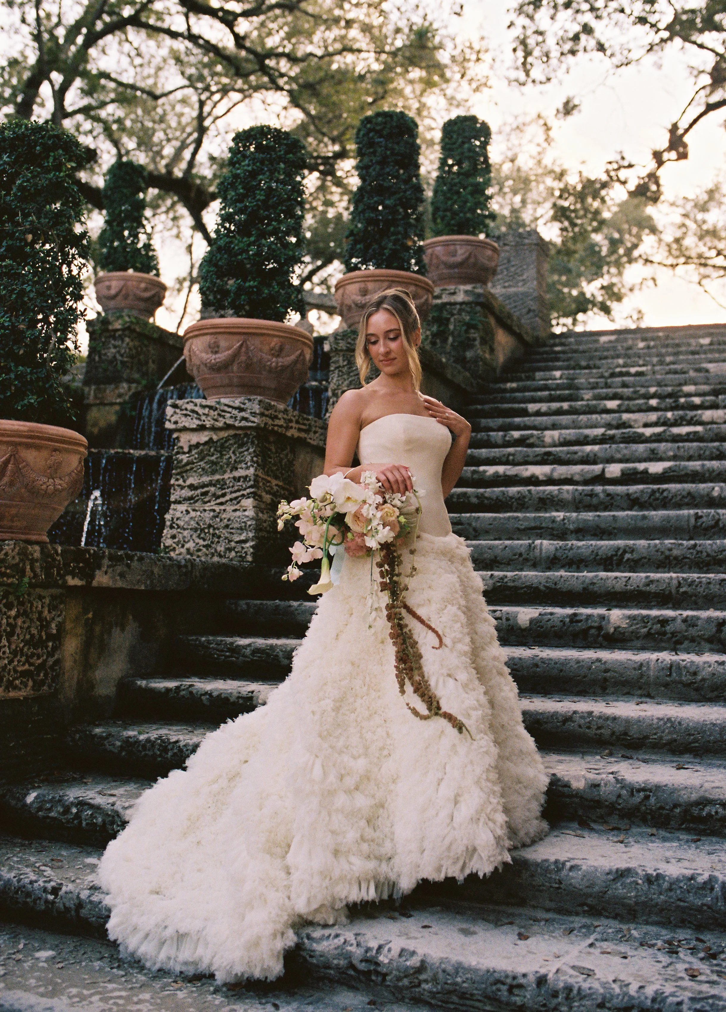 Bride standing on the historic stone staircase with cascading bouquet during portraits at Vizcaya Museum and Gardens. (Copy)
