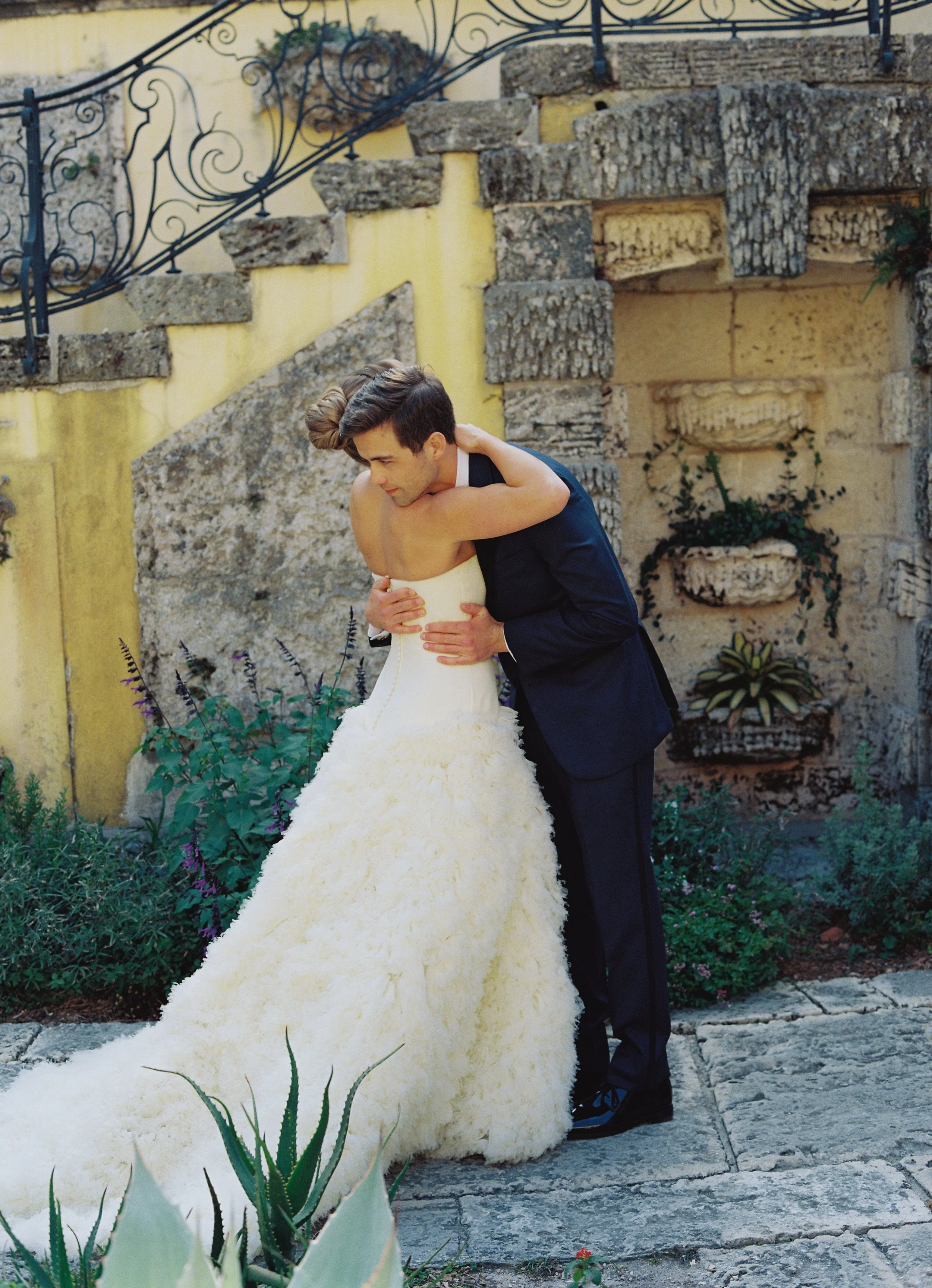 Bride and groom embracing in a quiet garden corner with historic stone stairs and greenery during their Vizcaya Museum and Gardens wedding. (Copy)