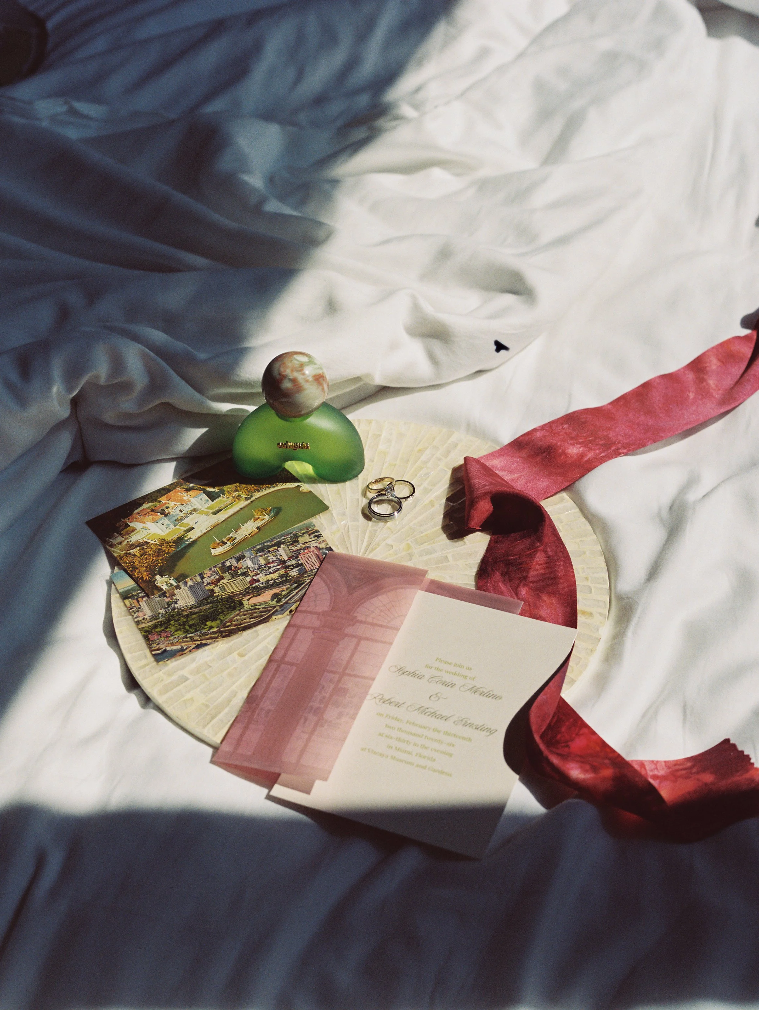 Wedding invitation suite with silk ribbon, perfume, rings, and vintage postcards styled for a romantic Vizcaya Museum and Gardens wedding in Miami.