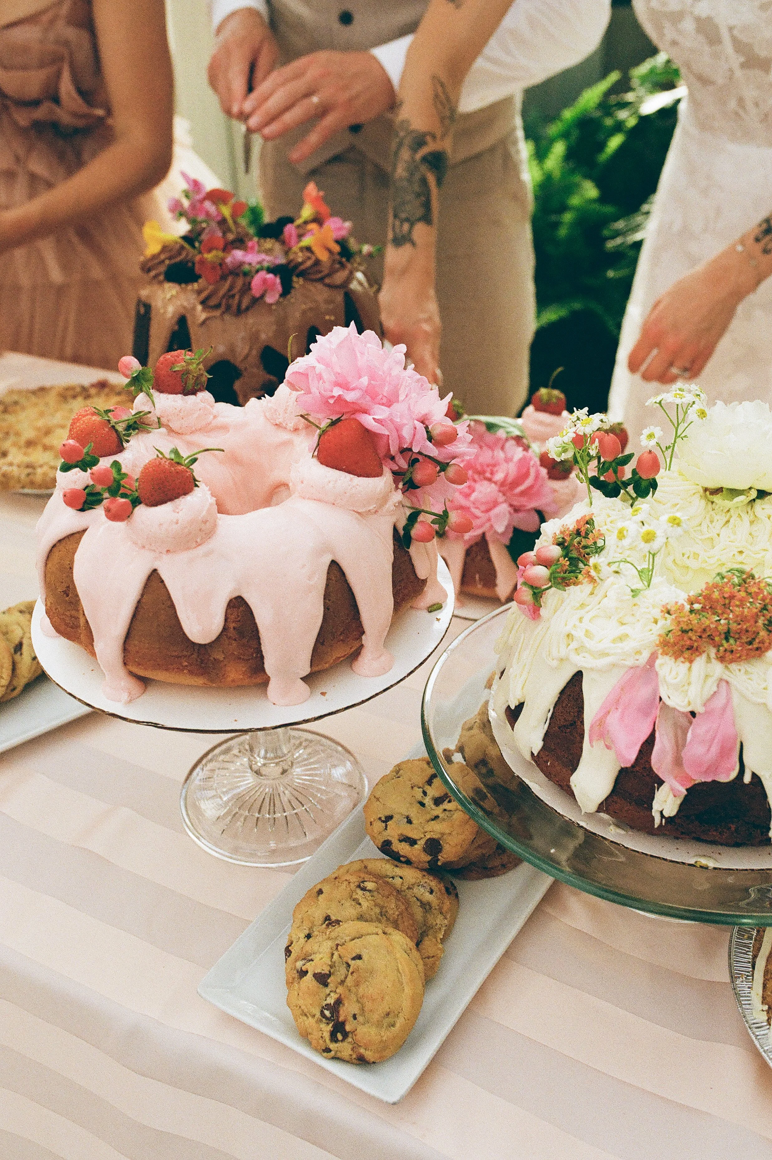 Wedding dessert table with floral-decorated cakes, strawberries, and cookies styled in a soft film wedding photography look