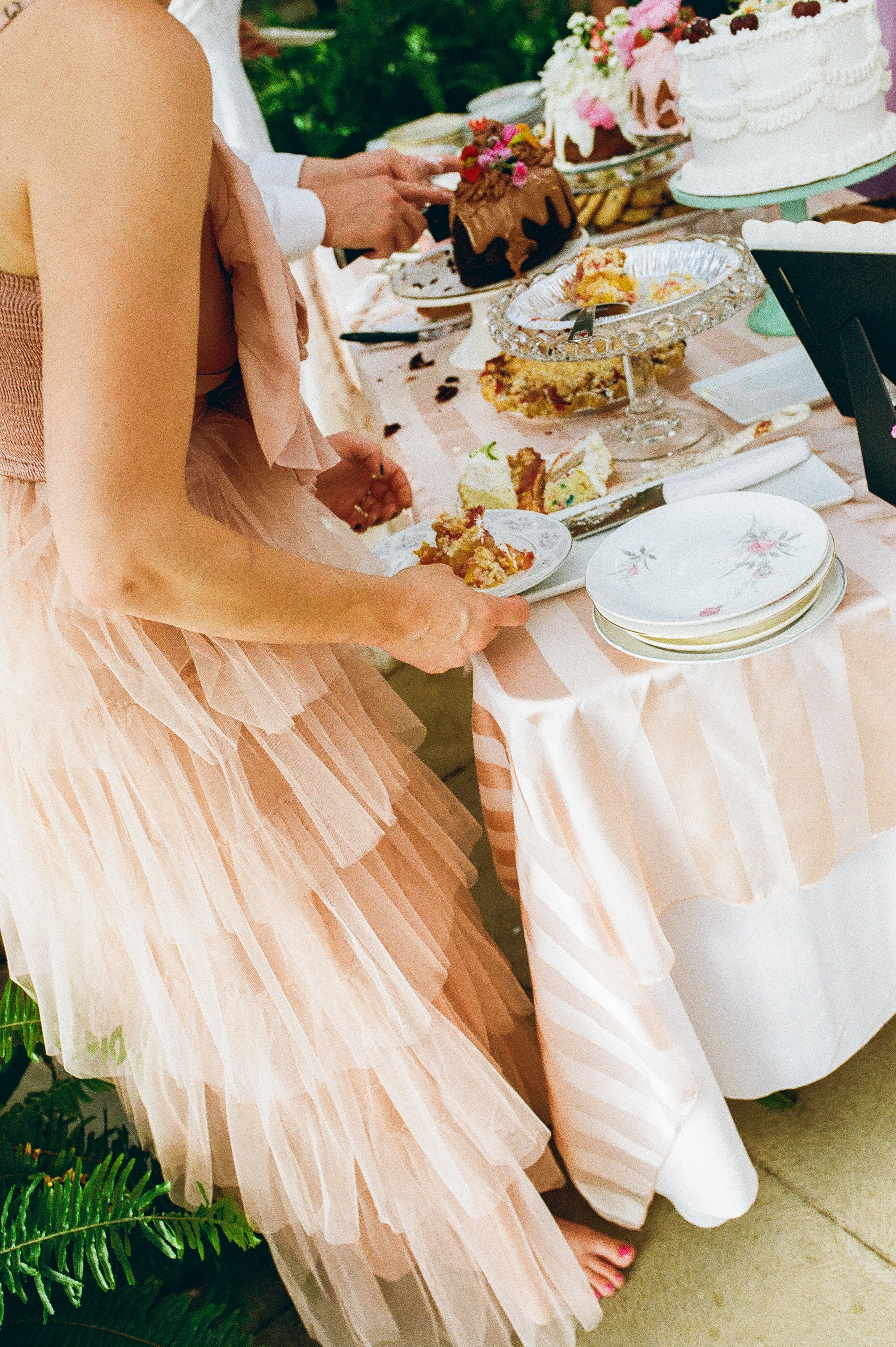 Guest serving dessert from a table filled with cakes and pastries, captured in a candid film wedding photography moment