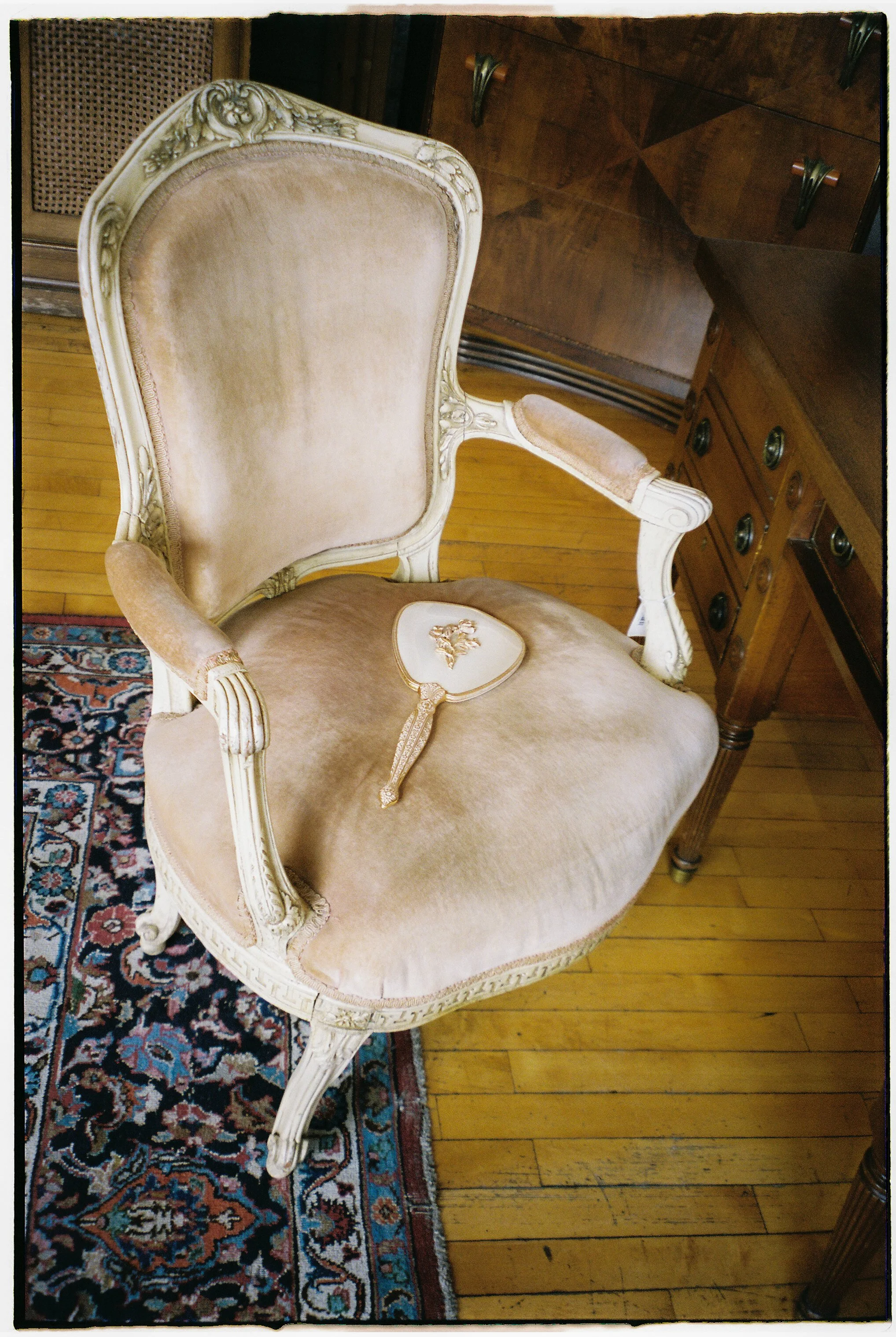 Ornate vintage chair with a decorative hand mirror placed on the seat