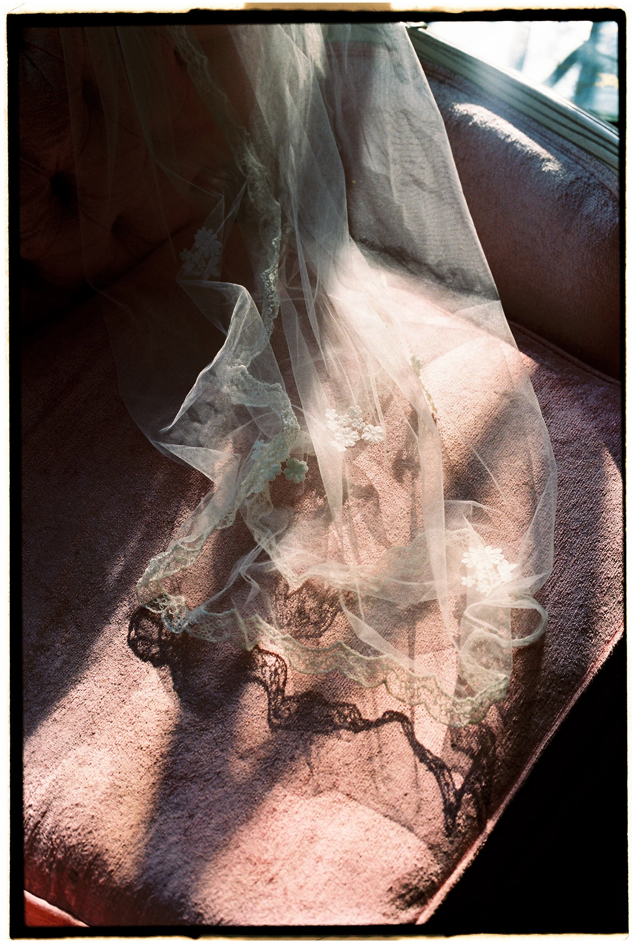 Bridal veil draped over a velvet chair with delicate lace details in natural window light