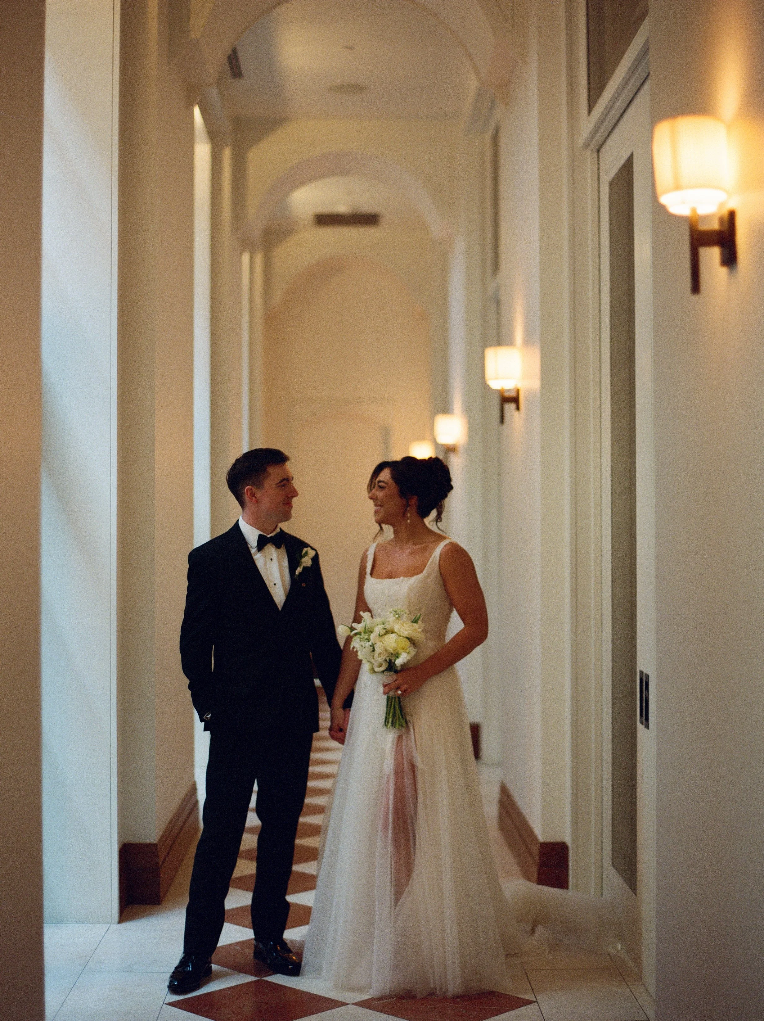 Newly married couple walking hand in hand through an elegant hallway at Shinola Hotel in Detroit