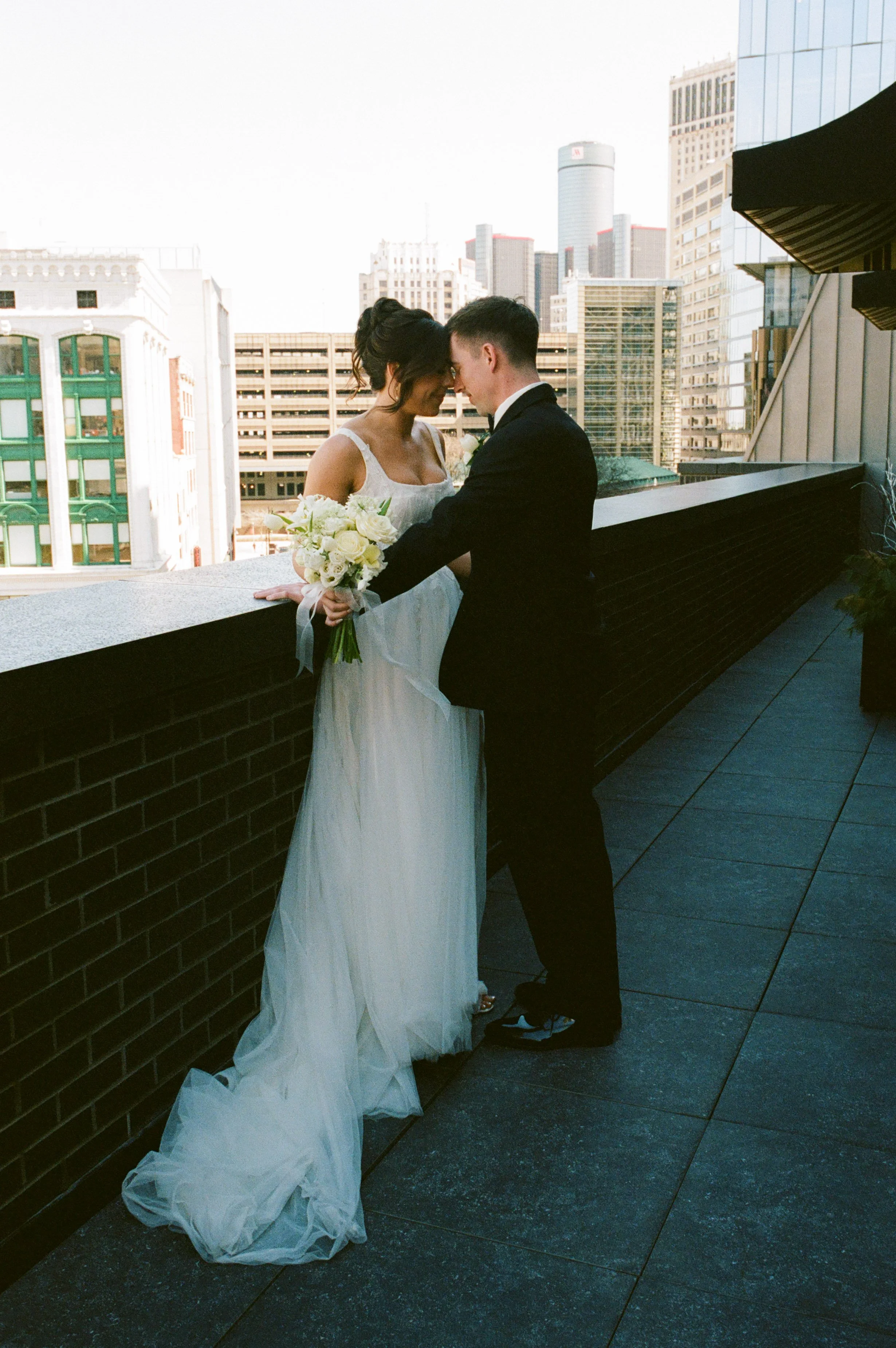 Bride and groom sharing a quiet moment on a rooftop terrace overlooking downtown Detroit