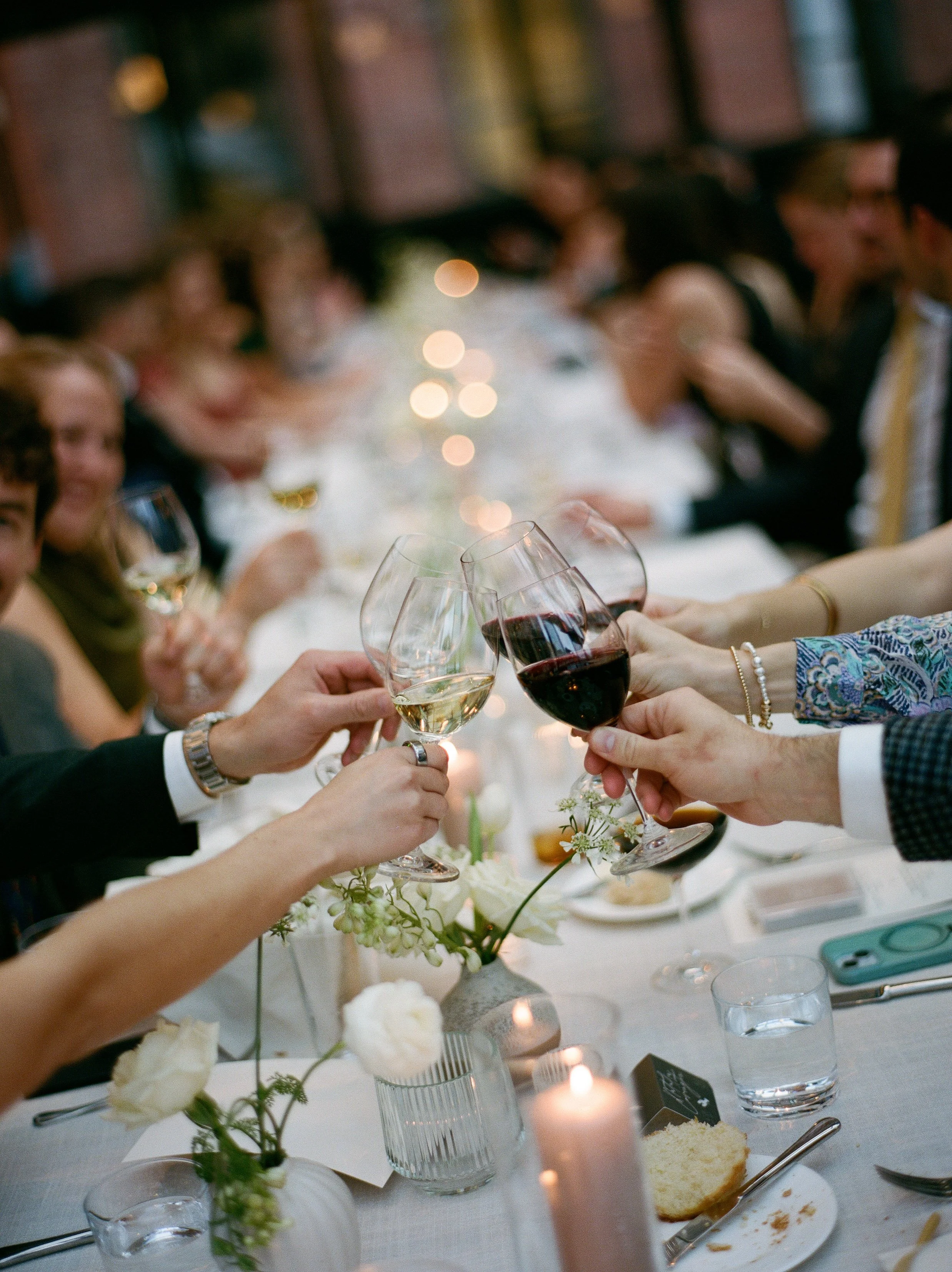 Guests clinking wine glasses together during an intimate candlelit wedding dinner reception