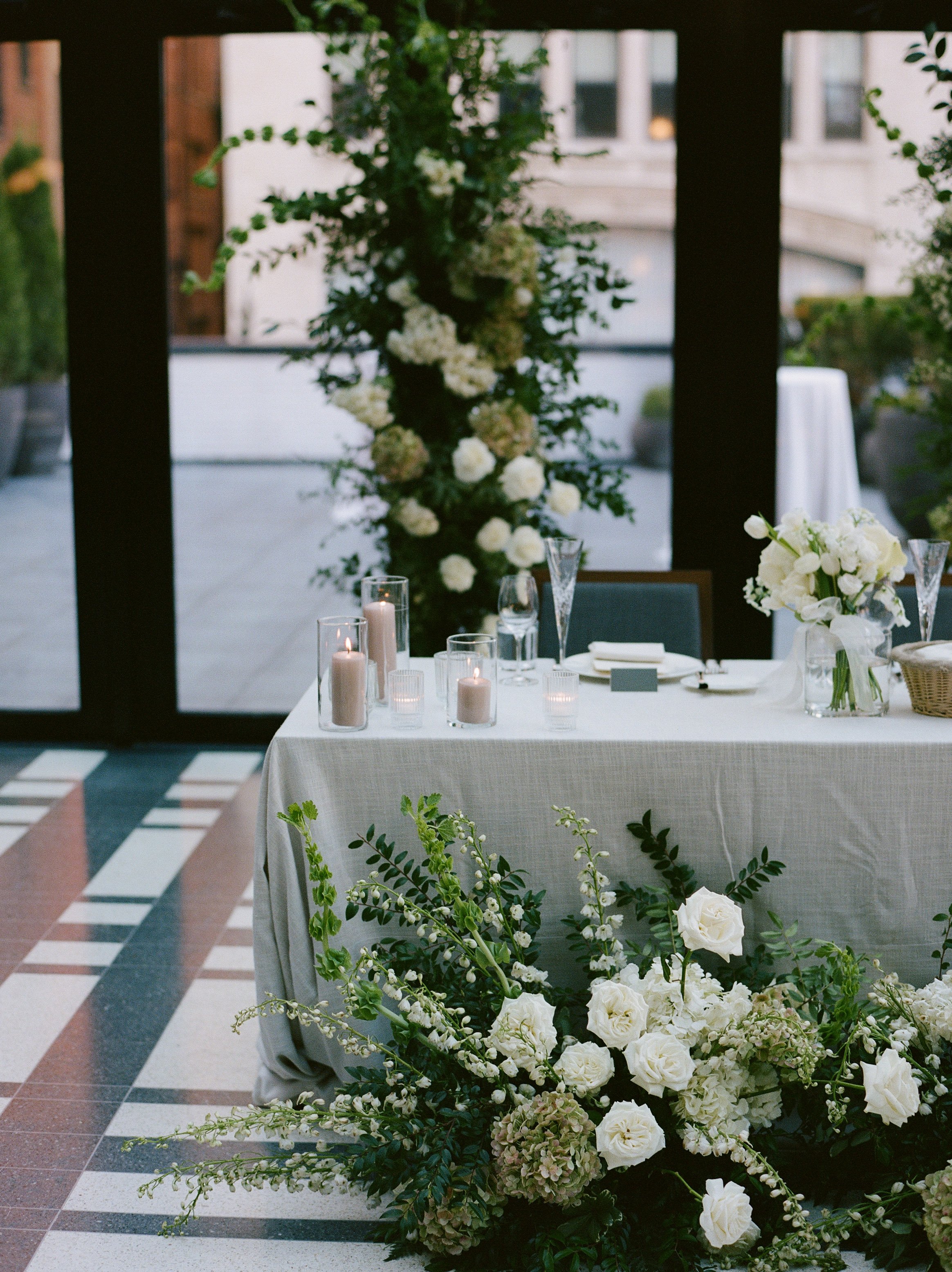 Elegant wedding reception table with white florals, candles, and greenery inside Shinola Hotel ballroom space