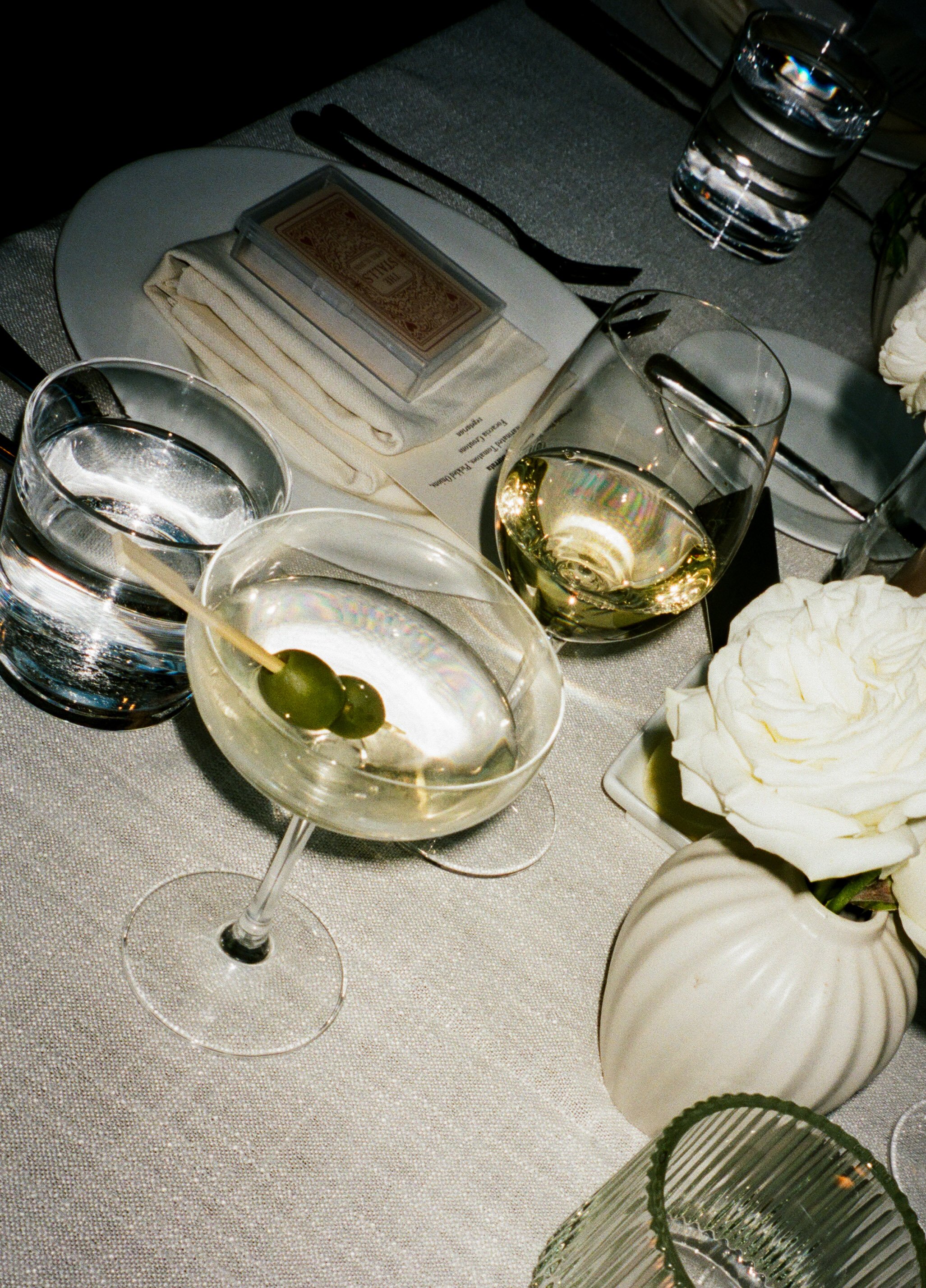 Martini with olives, white wine, and candlelit reception table details at an intimate wedding reception