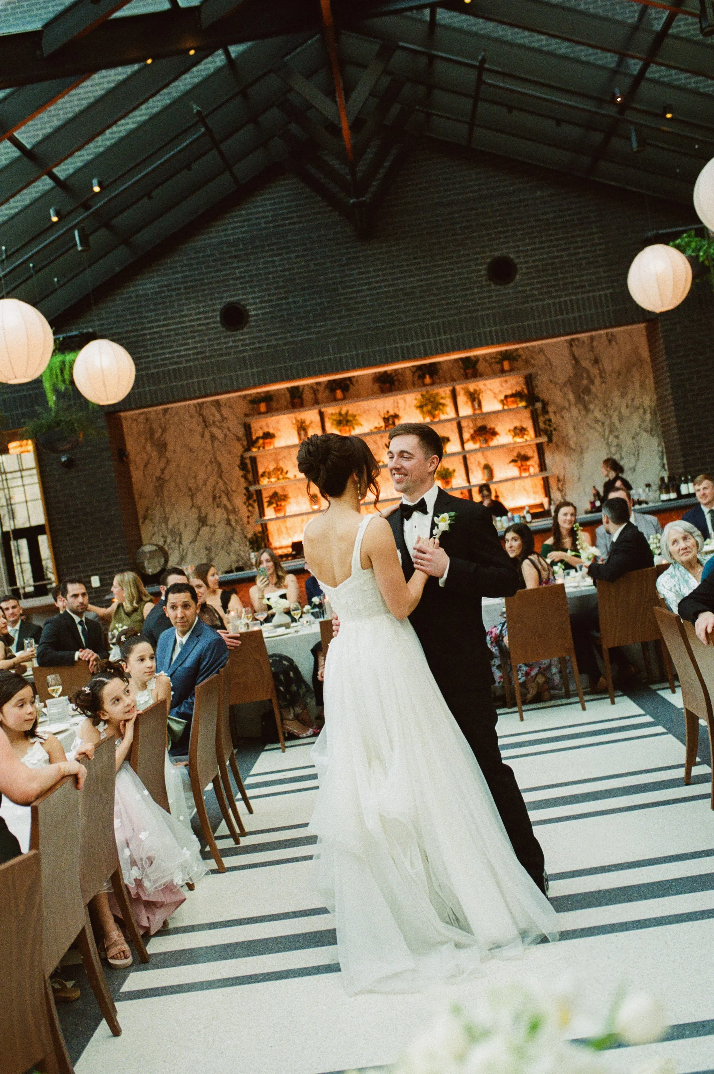 Bride and groom sharing their first dance beneath the glass atrium during their Shinola Hotel wedding reception