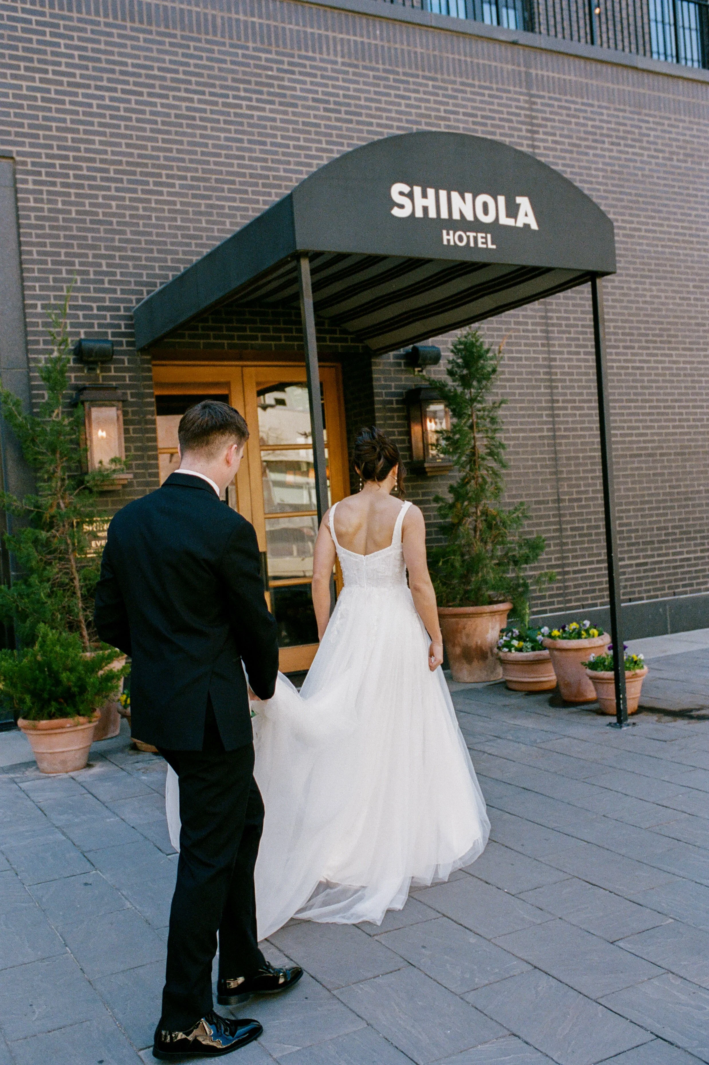 Bride and groom walking outside the entrance of Shinola Hotel in downtown Detroit after their wedding ceremony