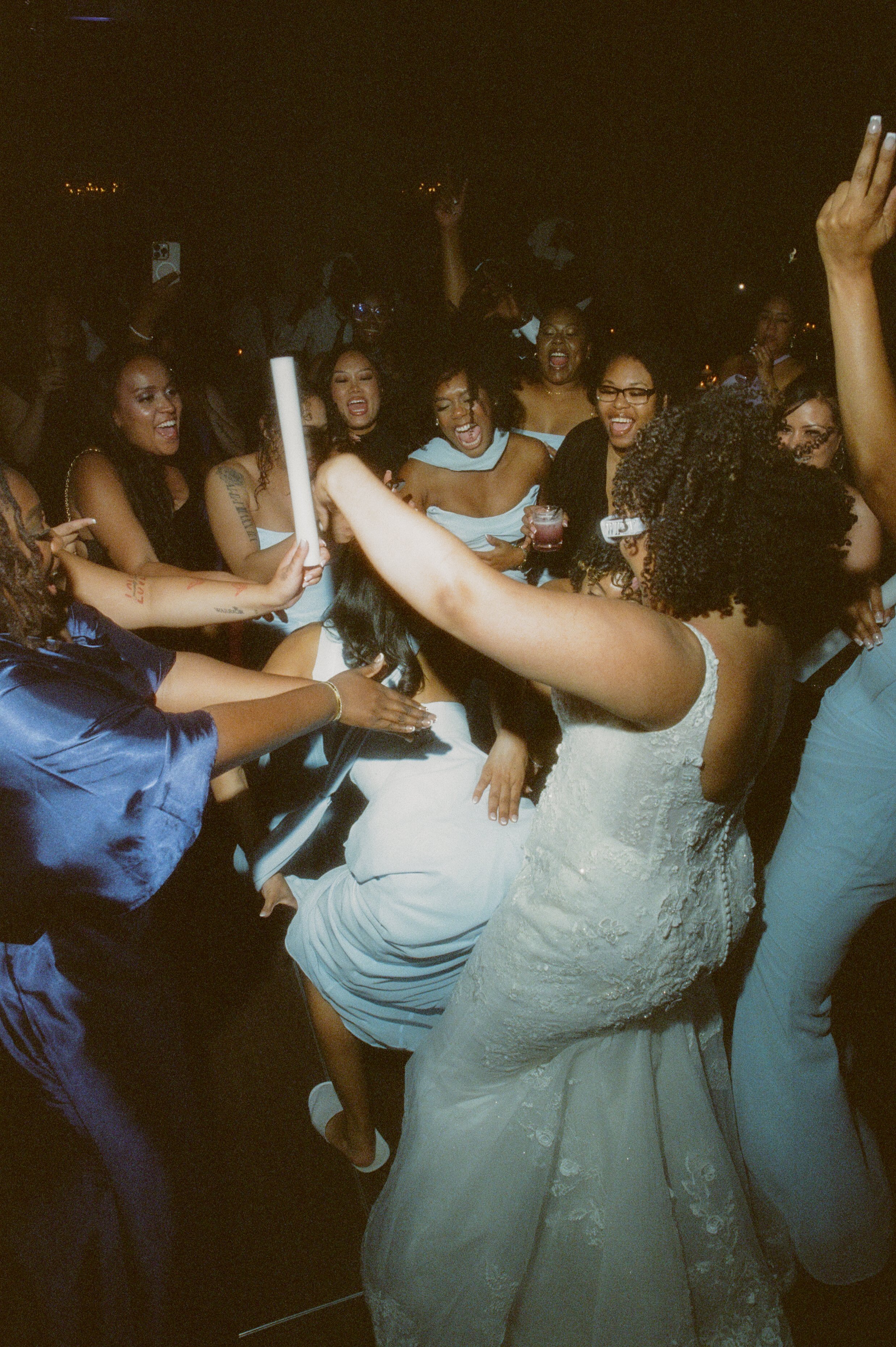 High-energy dance floor moment with the bride celebrating alongside friends during the wedding reception with cinematic film photography vibes