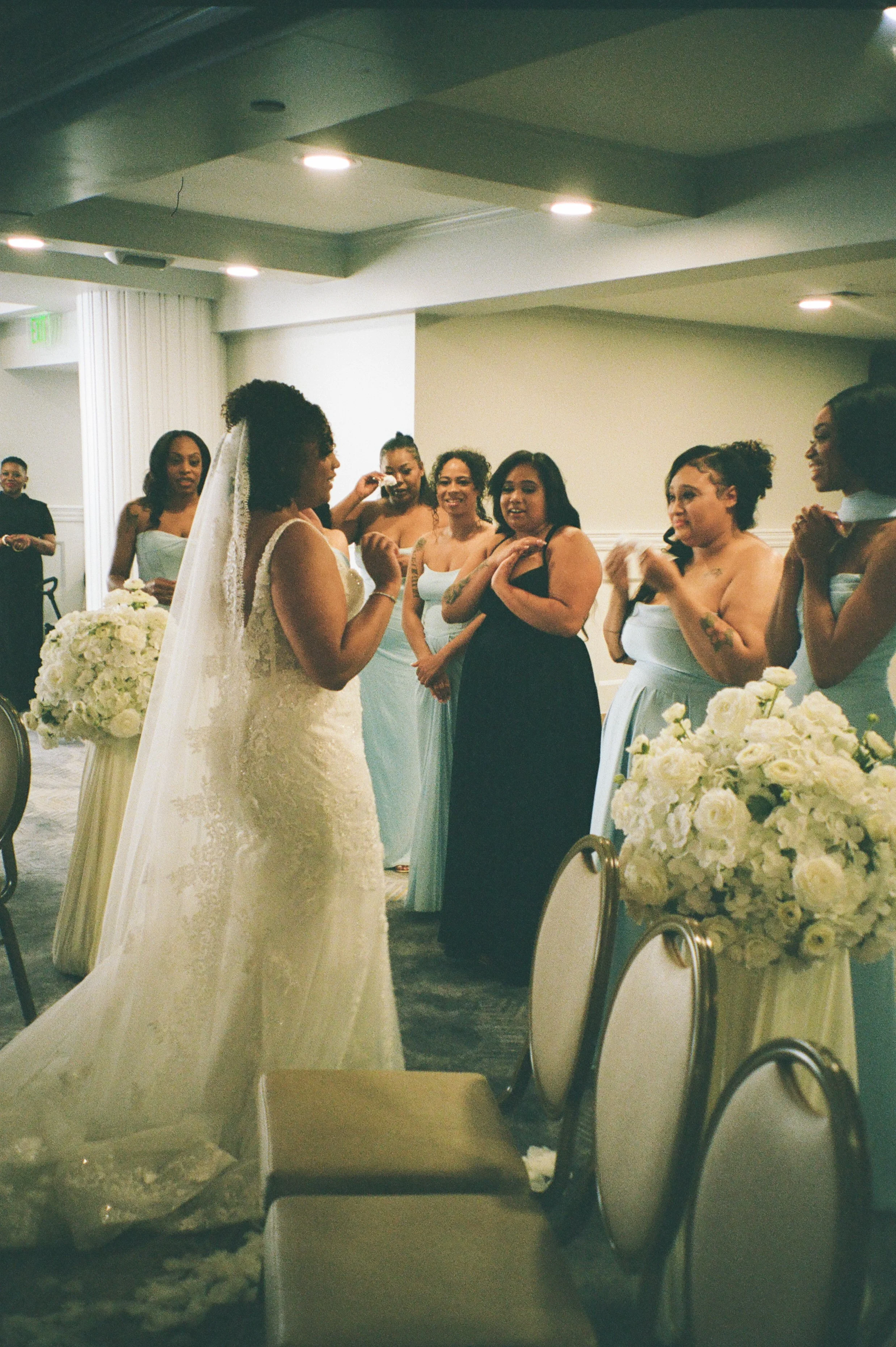 Emotional moment between the bride and bridesmaids before the ceremony surrounded by white floral arrangements