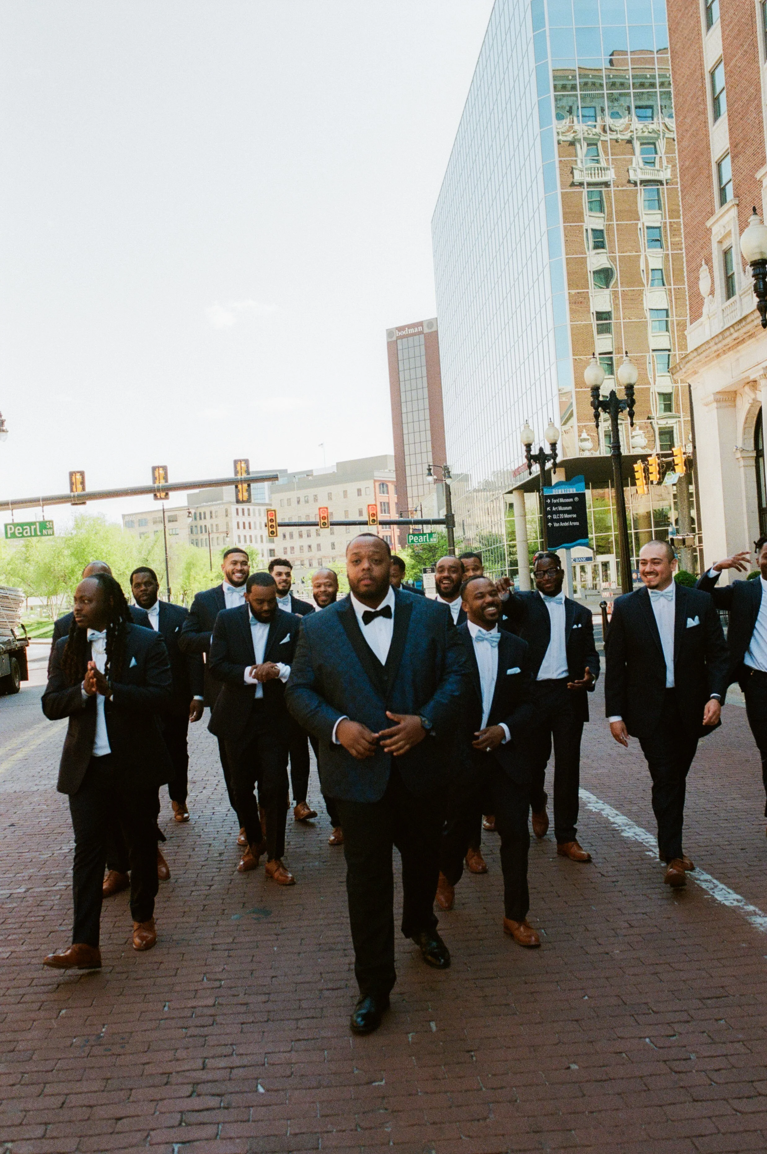 Groom and groomsmen walking through downtown Grand Rapids in black tuxedos before the wedding ceremony