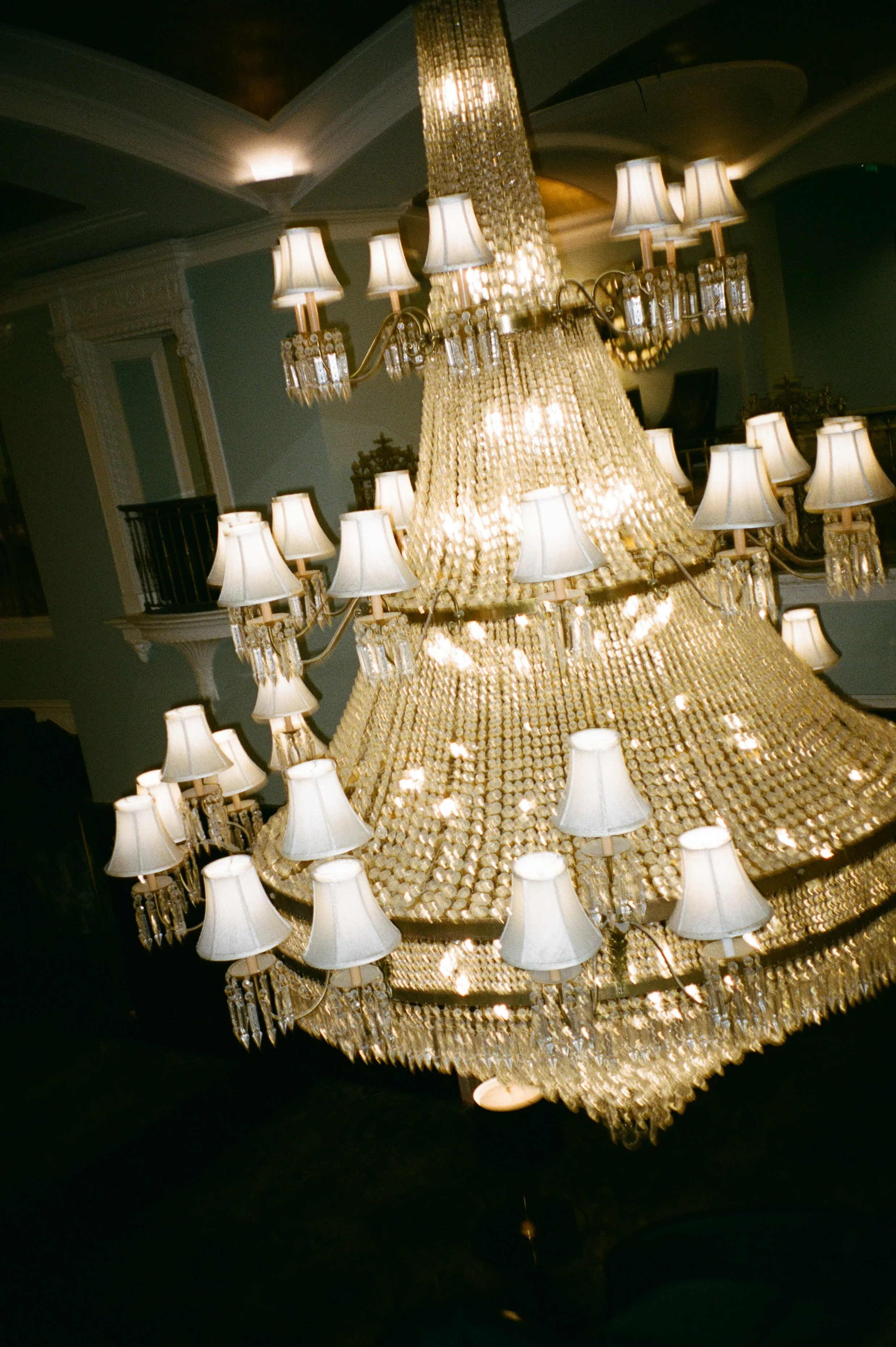 Elegant crystal chandelier hanging inside a historic ballroom photographed with cinematic film photography aesthetics