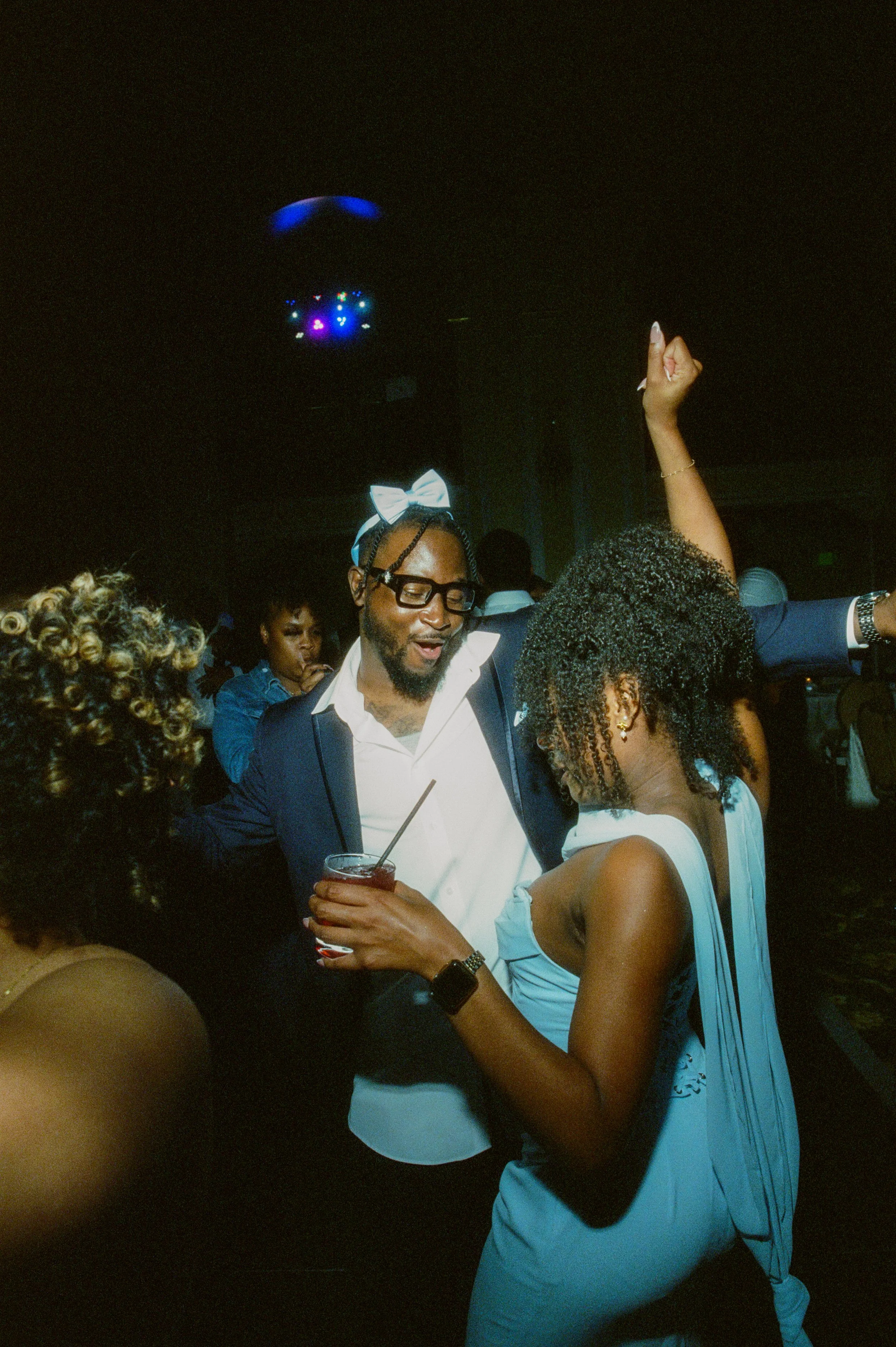 Wedding guest dancing on the reception dance floor with glow sticks and dramatic party lighting captured with cinematic film photography vibes
