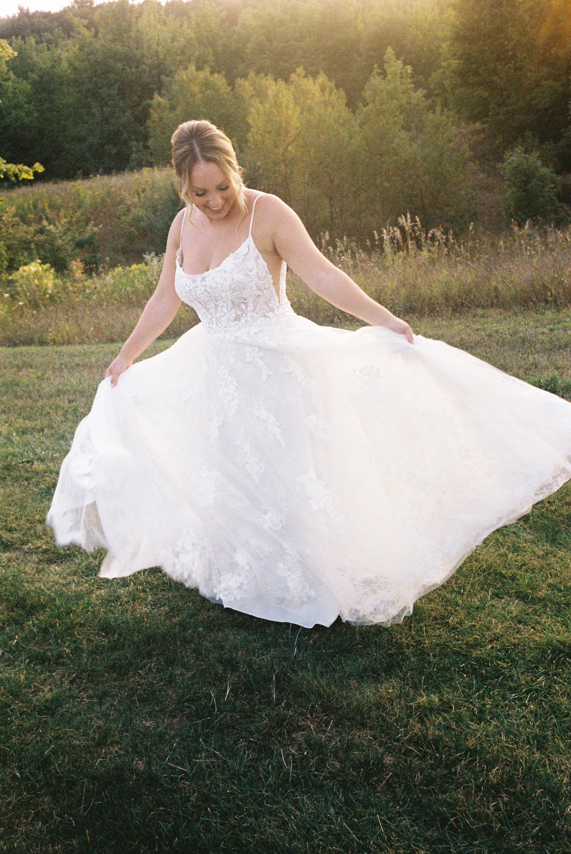 Bride twirling in her wedding dress during golden hour portraits at a Northern Michigan vineyard wedding surrounded by rolling countryside views.
